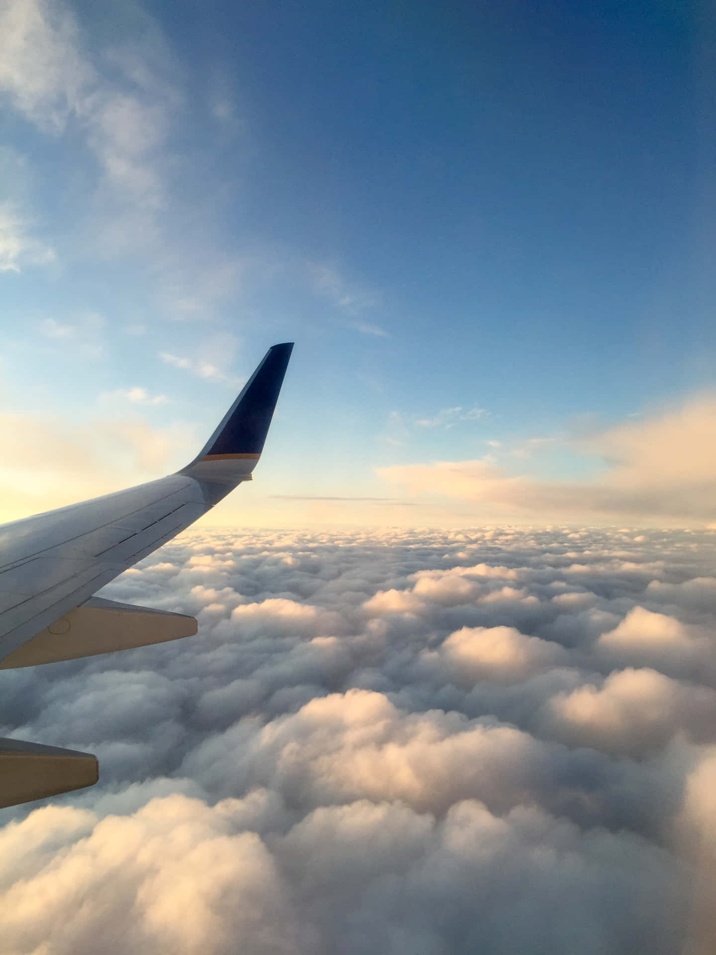日出時在蓬鬆雲層上翱翔的飛機機翼