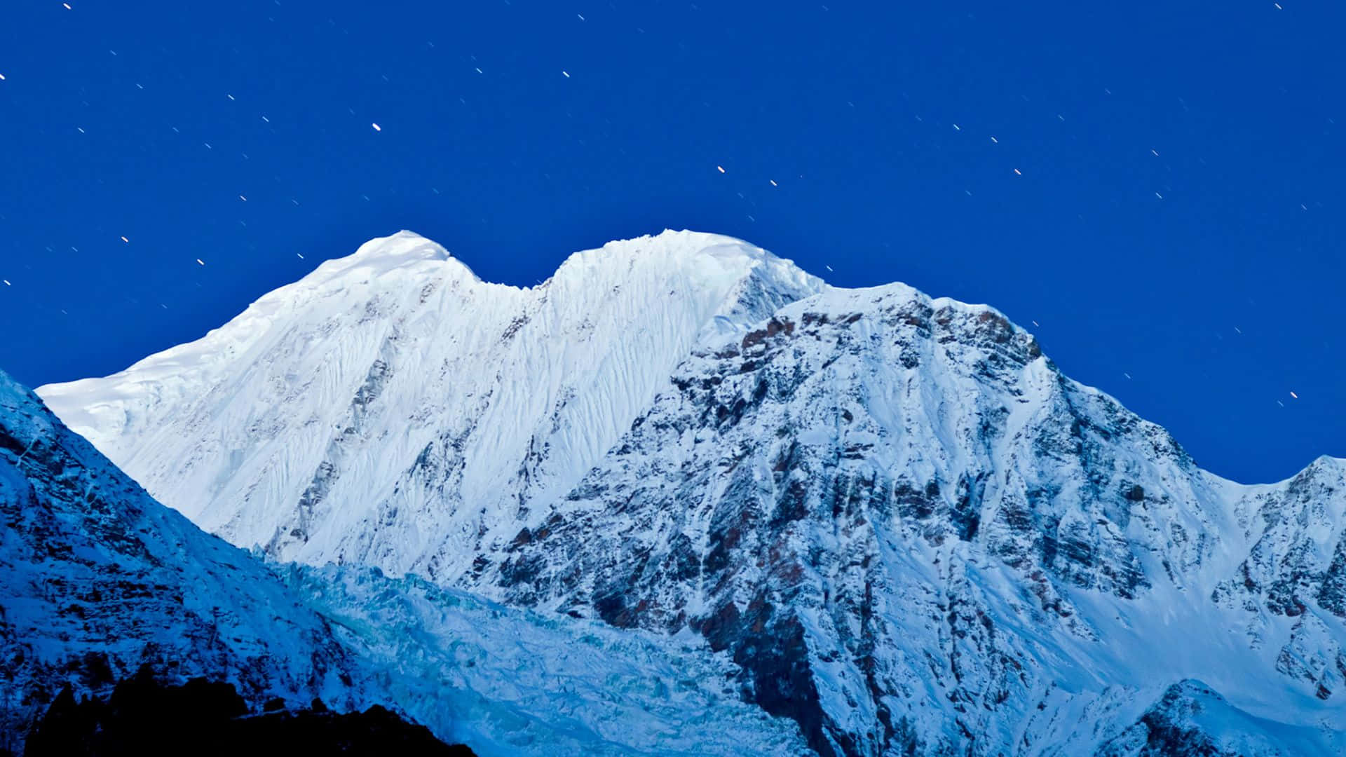 在星空下，深藍色調的雪山山峰。