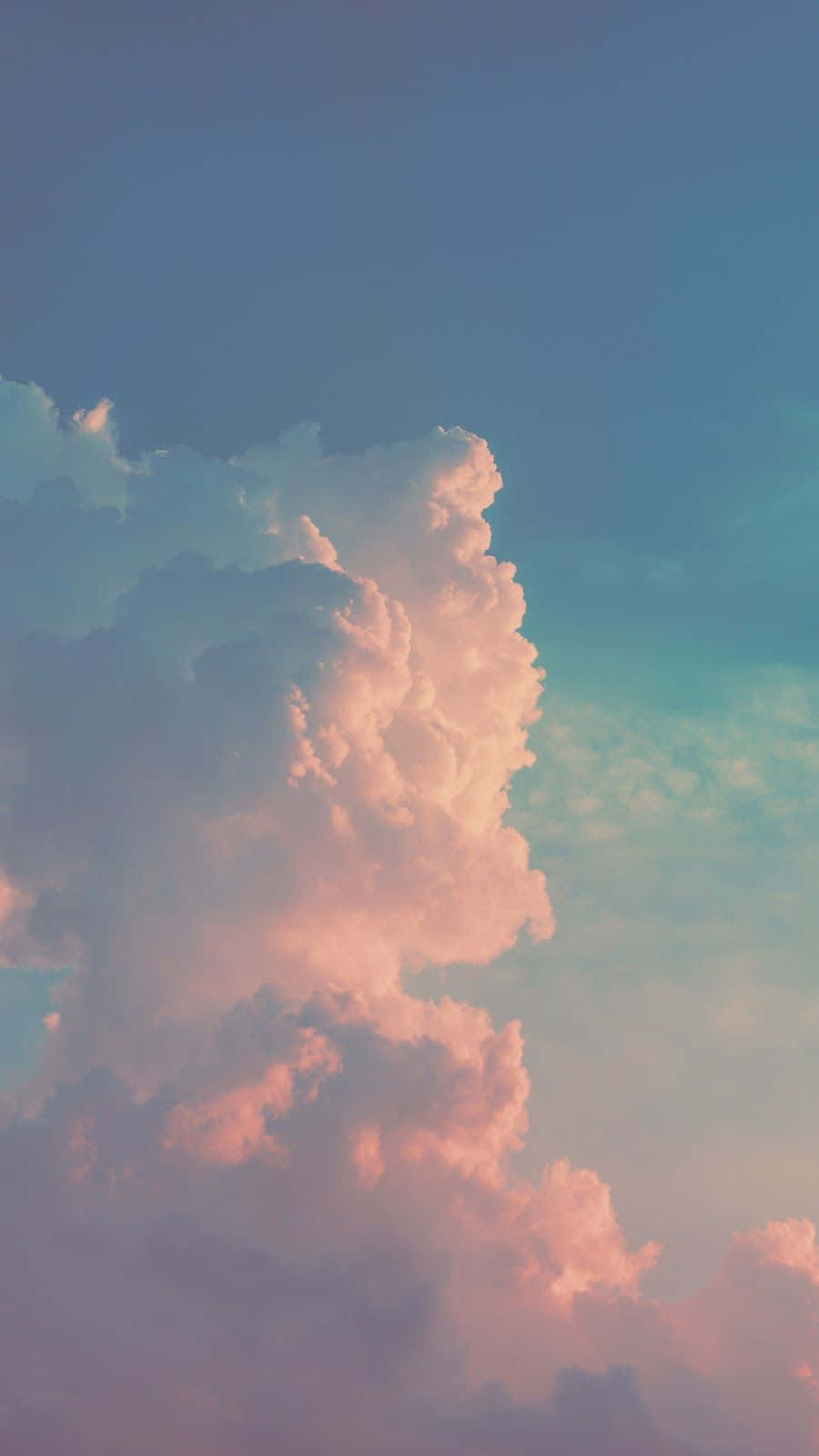 「飛速流動的天空，飄浮著蓬鬆白雲」 壁紙 — 高聳的積雲沐浴在柔和的粉紅和青綠光中，映襯著漸變的天空。