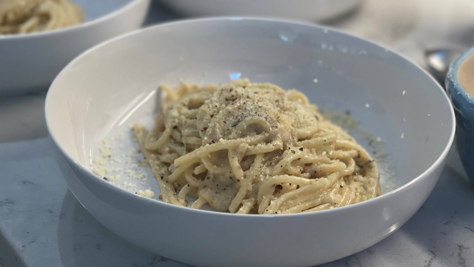 餐廳供應 Cacio E Pepe 壁紙 — 一個白色碗中的奶油意粉卡邦尼拉特寫，上面撒有磨碎芝士和黑胡椒。