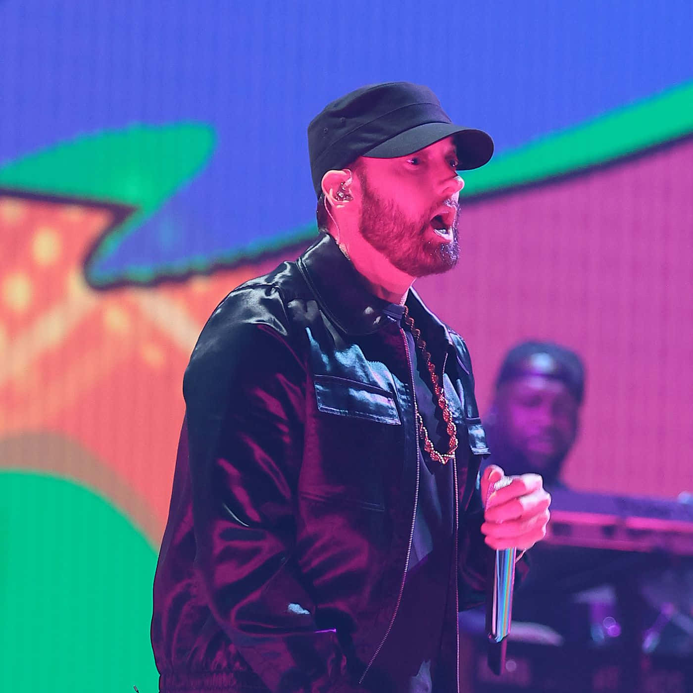 Eminem 桌布 壁紙 — 饒舌歌手 Emcee 在充滿活力的粉紅色和藍色舞台燈光下，熱情地拿著麥克風表演。