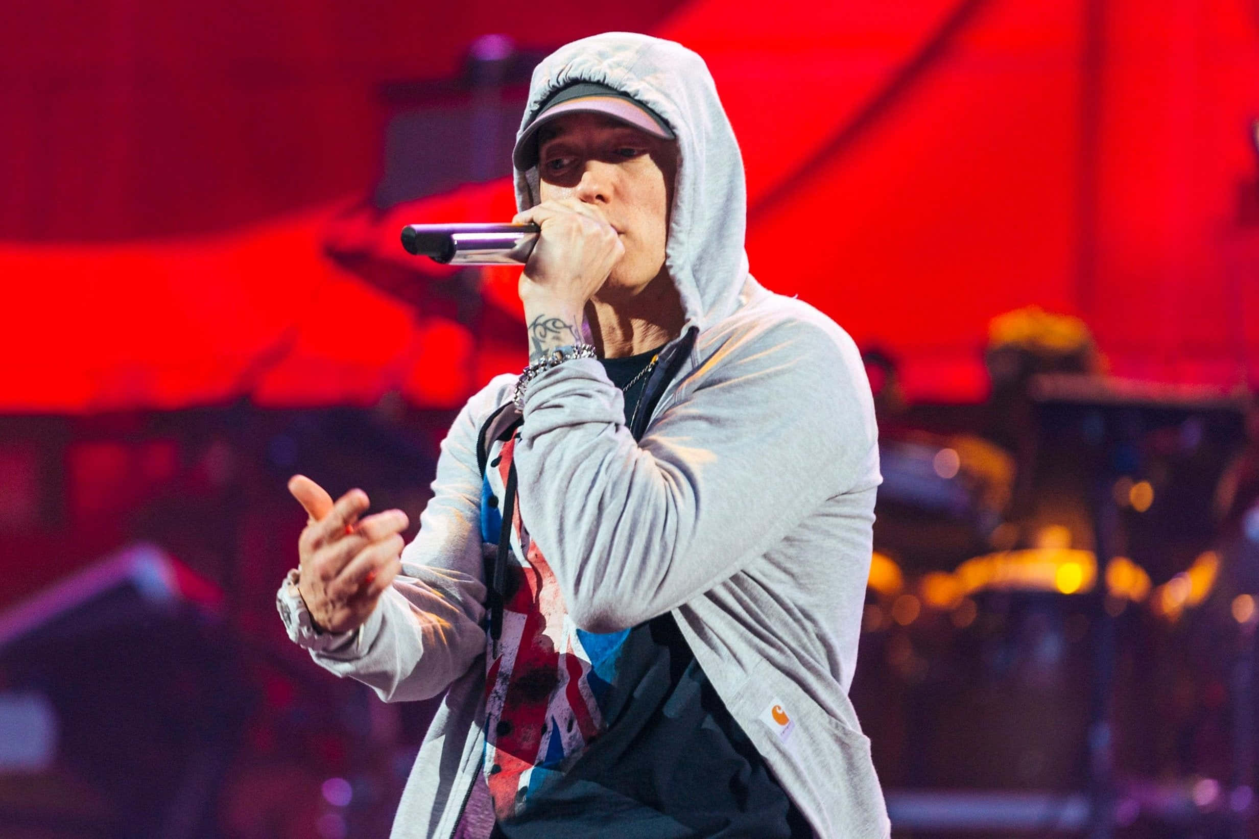 Eminem 桌布 壁紙 — 饒舌歌手Eminem在充滿活力的紅光下，將麥克風靠近嘴邊，在舞台上熱情表演。