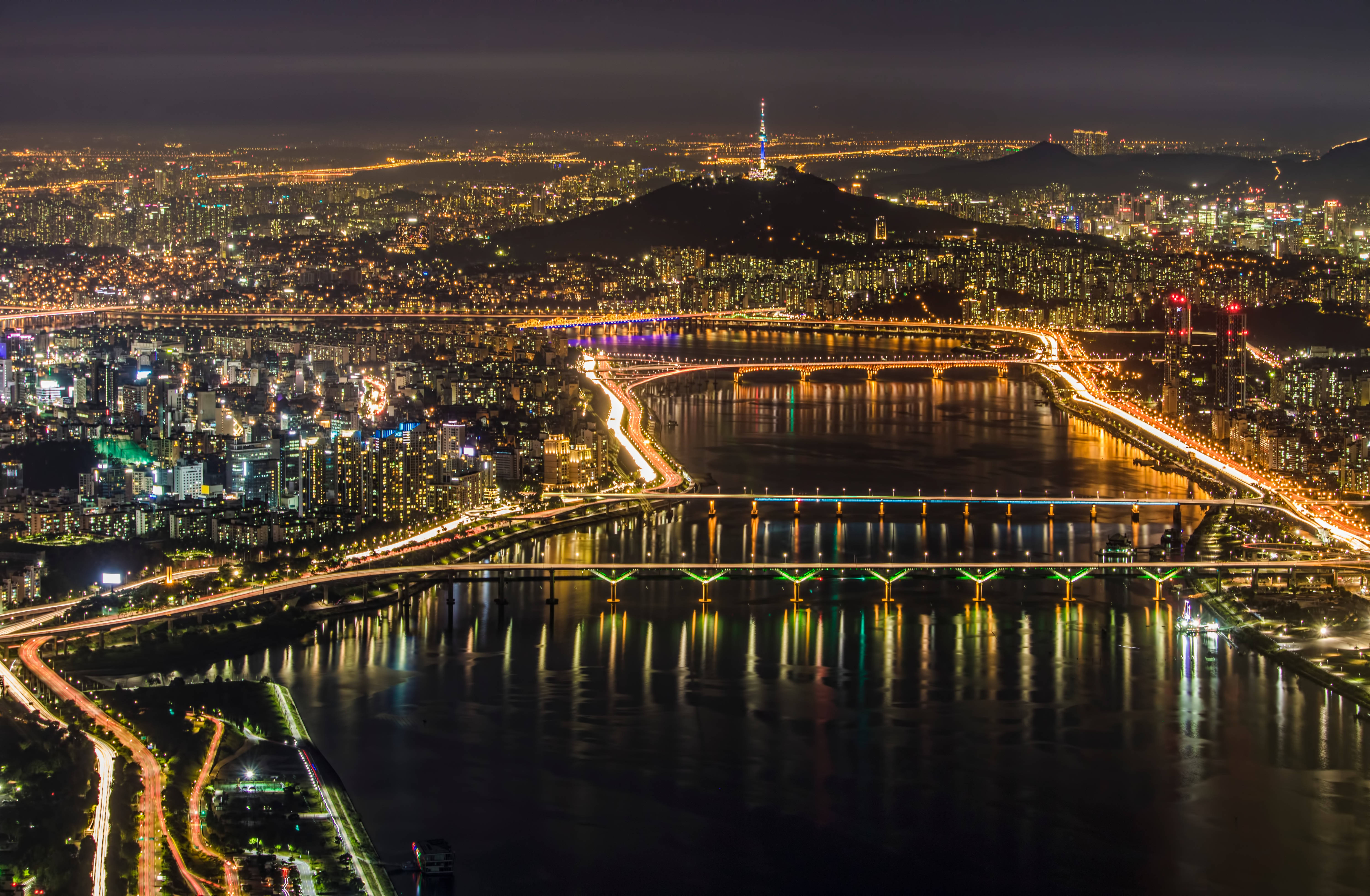 首爾夜景 燈光璀璨 壁紙 — 首爾夜間空中景觀，燈火輝煌的城市天際線，發光的橋樑橫跨黑暗的河流，N首爾塔矗立在山丘上。