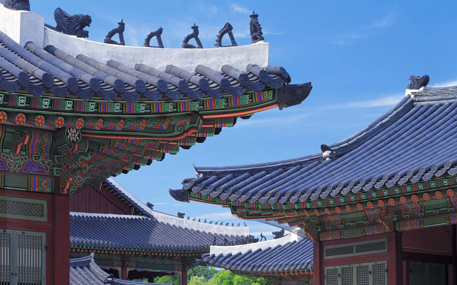 色彩繽紛的傳統韓國寺廟屋頂，帶有藍色瓦片和裝飾性屋簷，以藍天為背景。