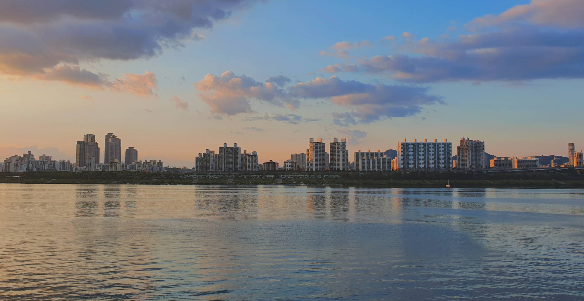 夕陽下的城市天際線倒映在平靜的河水之中。