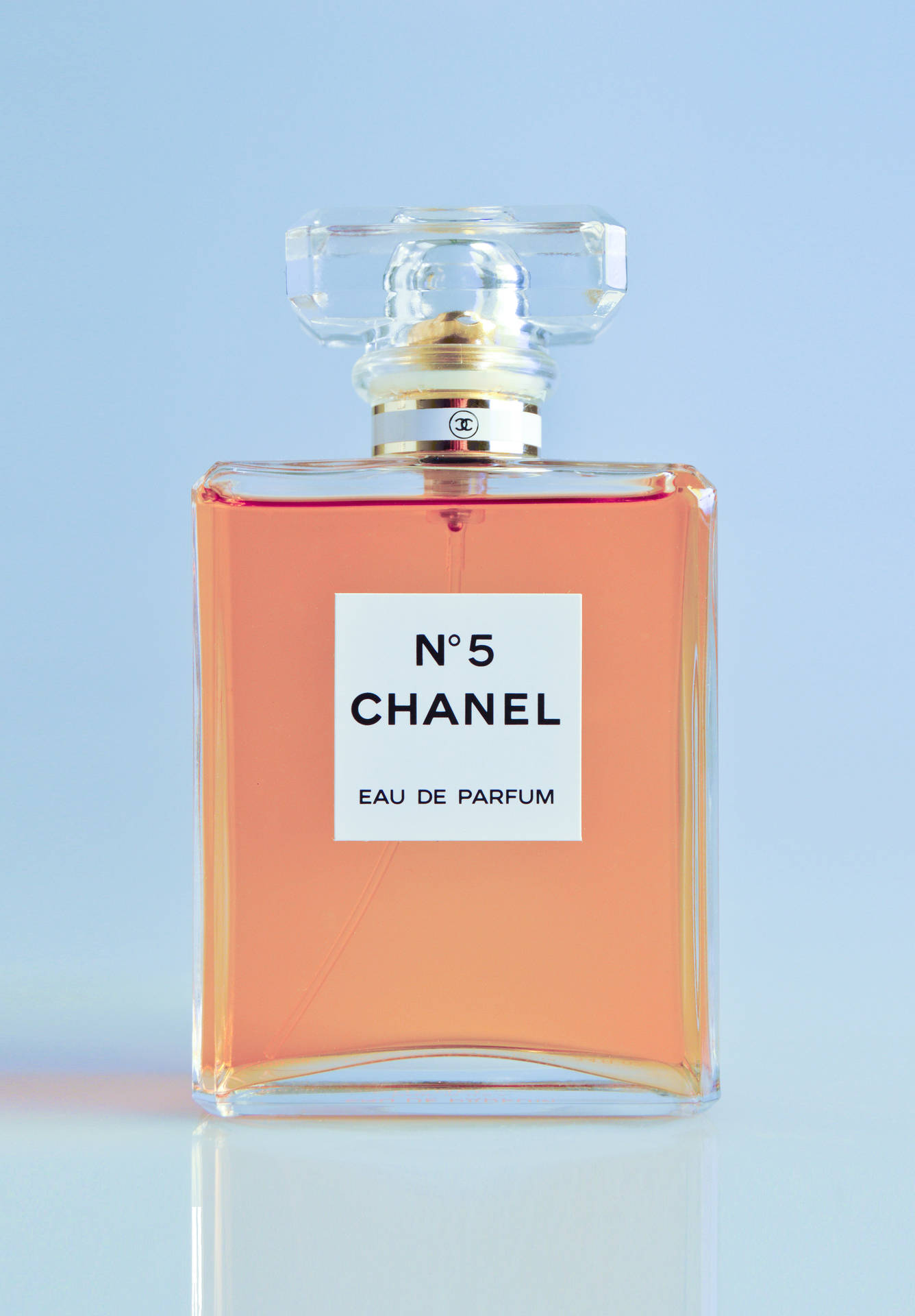 Chanel No 5 香水瓶，裝有桃色液體，置於反光表面上。