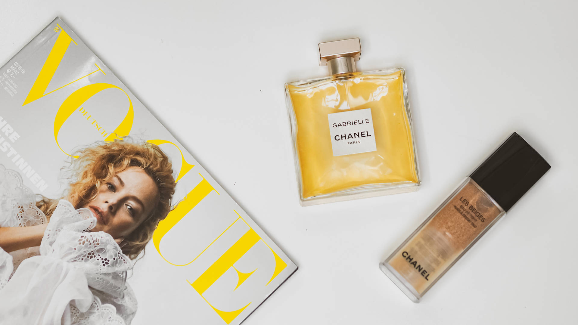 白色背景上的Vogue雜誌和Chanel香水及粉底。