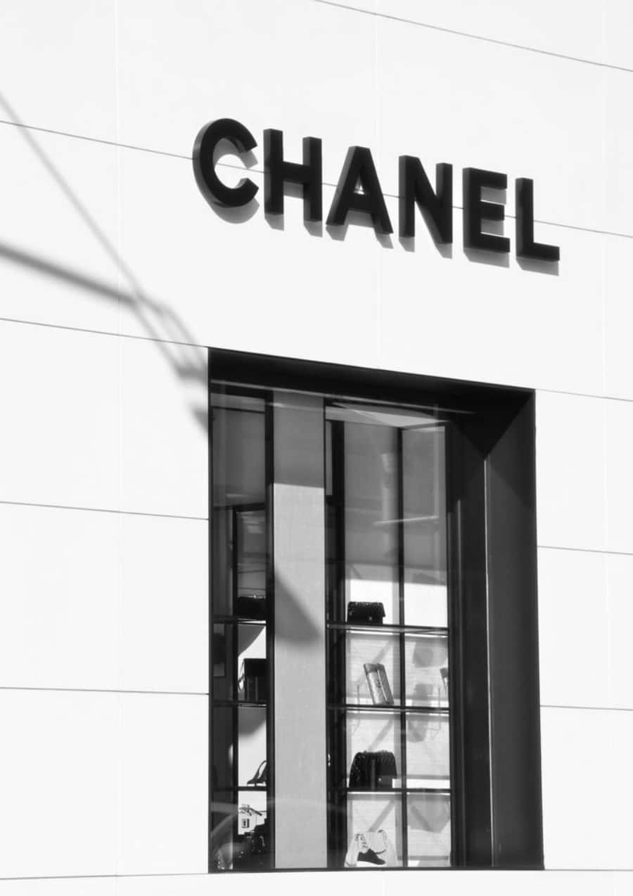 香奈兒的優雅與 sophistication 壁紙 — 大膽的黑色CHANEL標誌在玻璃展示窗上方的純白外牆上投下銳利陰影。