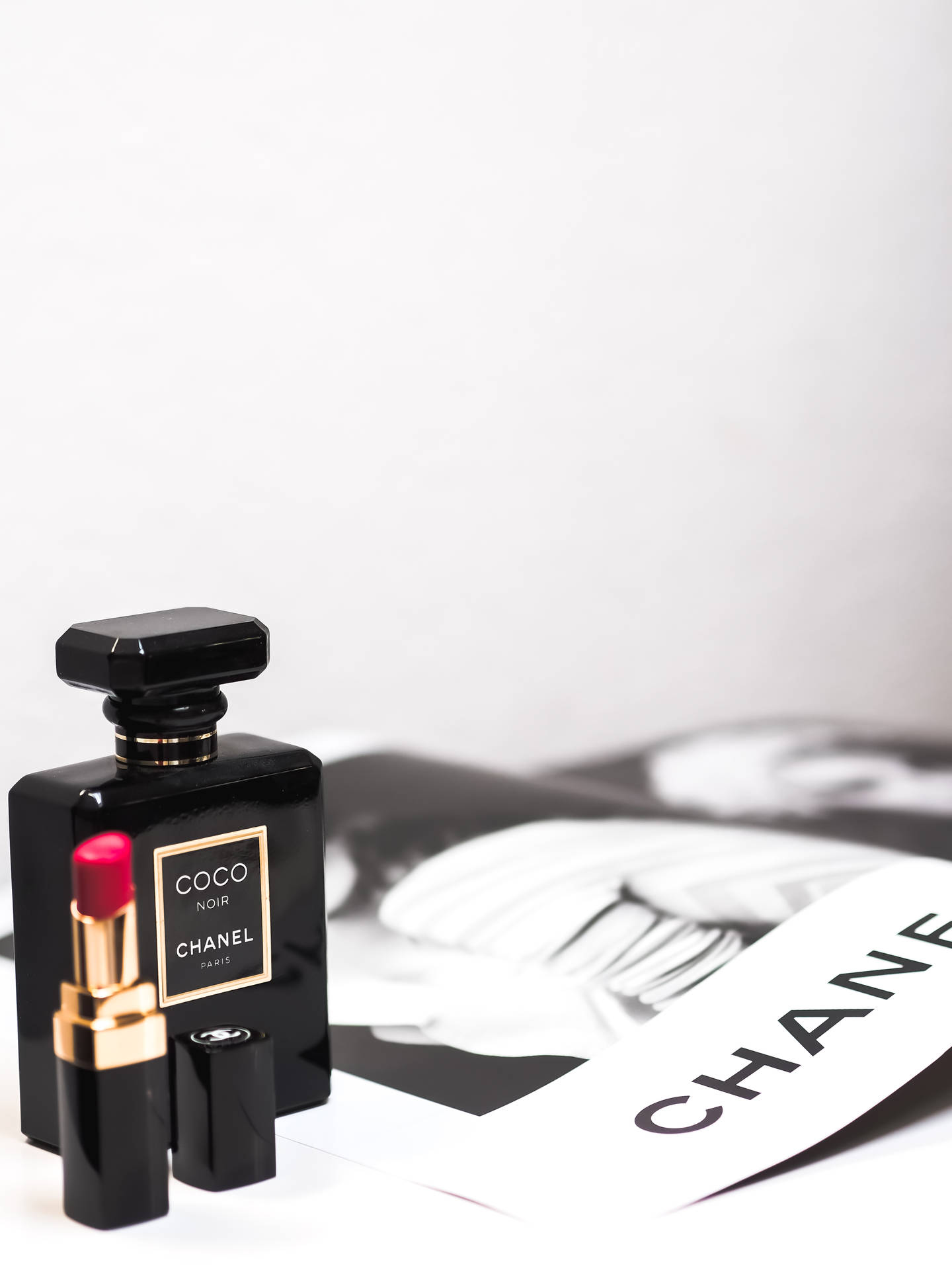Chanel 香水瓶和口紅在白色上，附雜誌。
