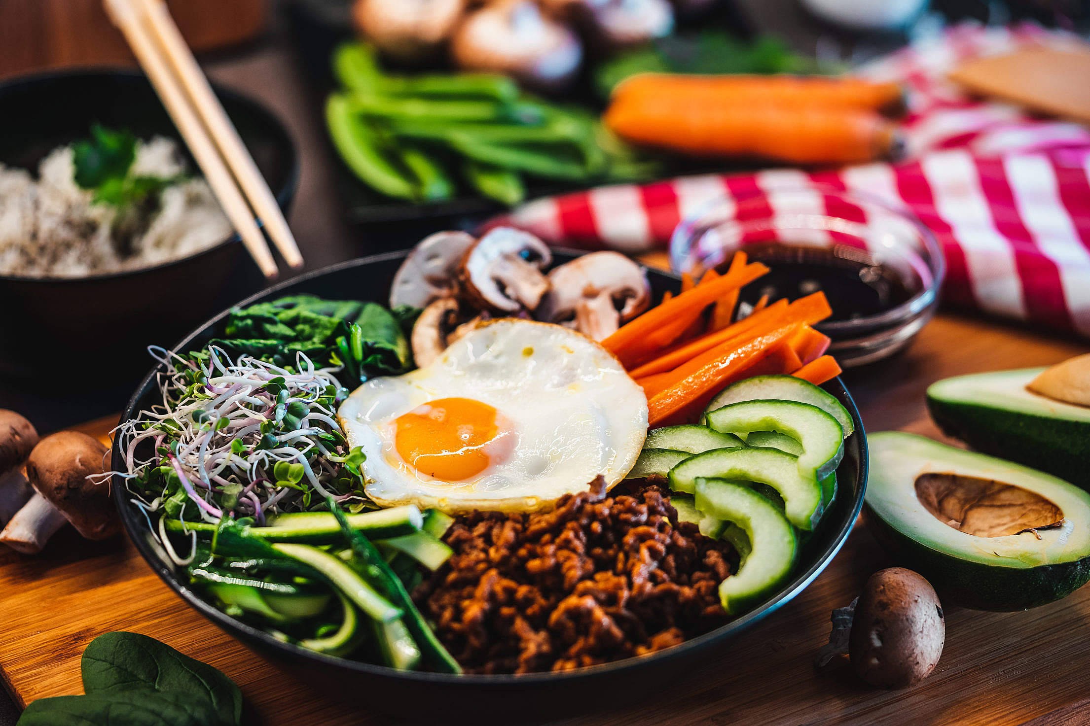 香氣四溢健康的韓式拌飯 壁紙 — 一碗色彩繽紛的韓國石鍋拌飯，上面放著太陽蛋和新鮮蔬菜，置於木桌上。