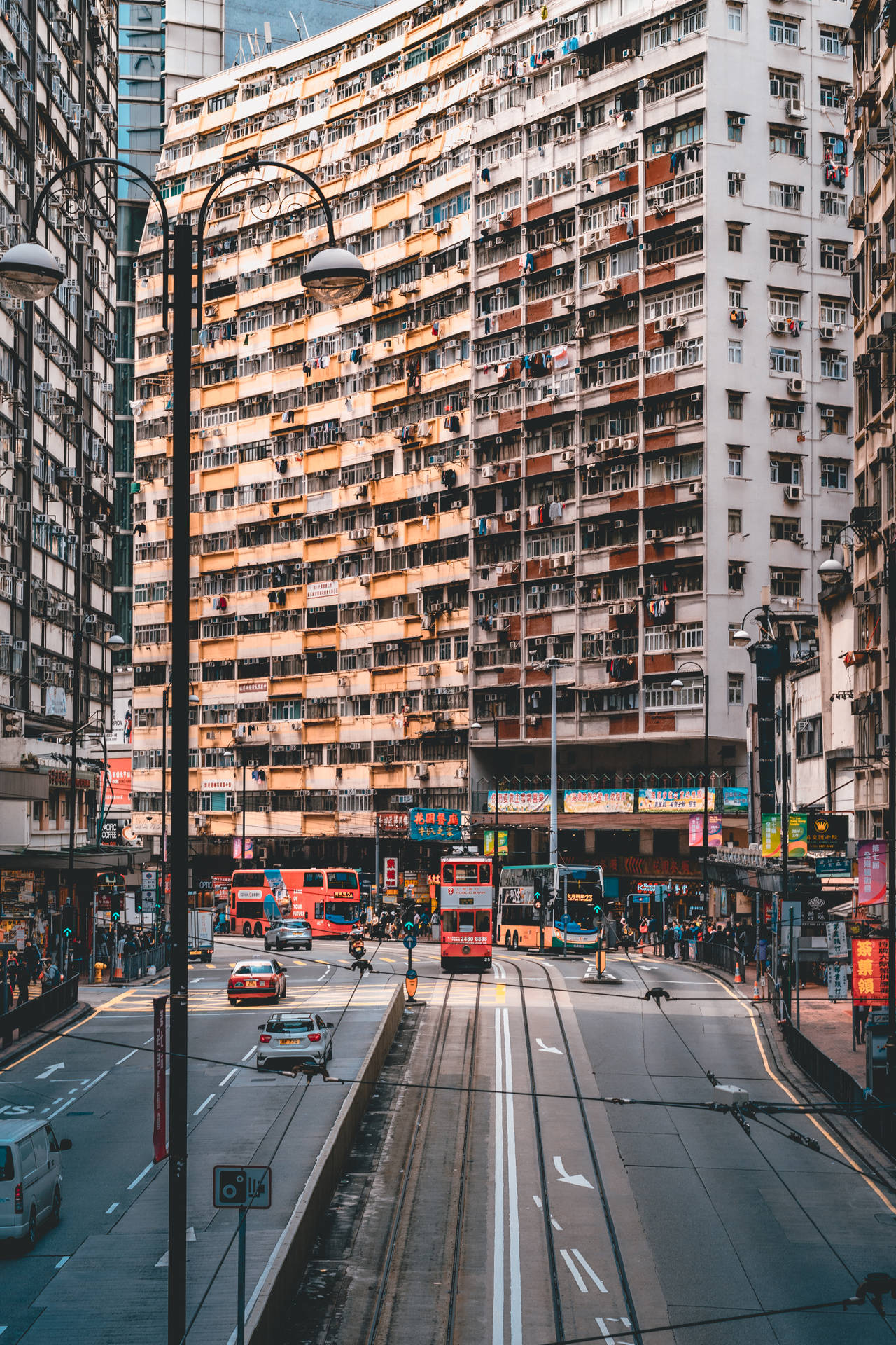 香港北角 壁紙 — 一條繁忙的香港街道，有紅色雙層電車和高聳的公寓大樓，佈滿陽台和空調。