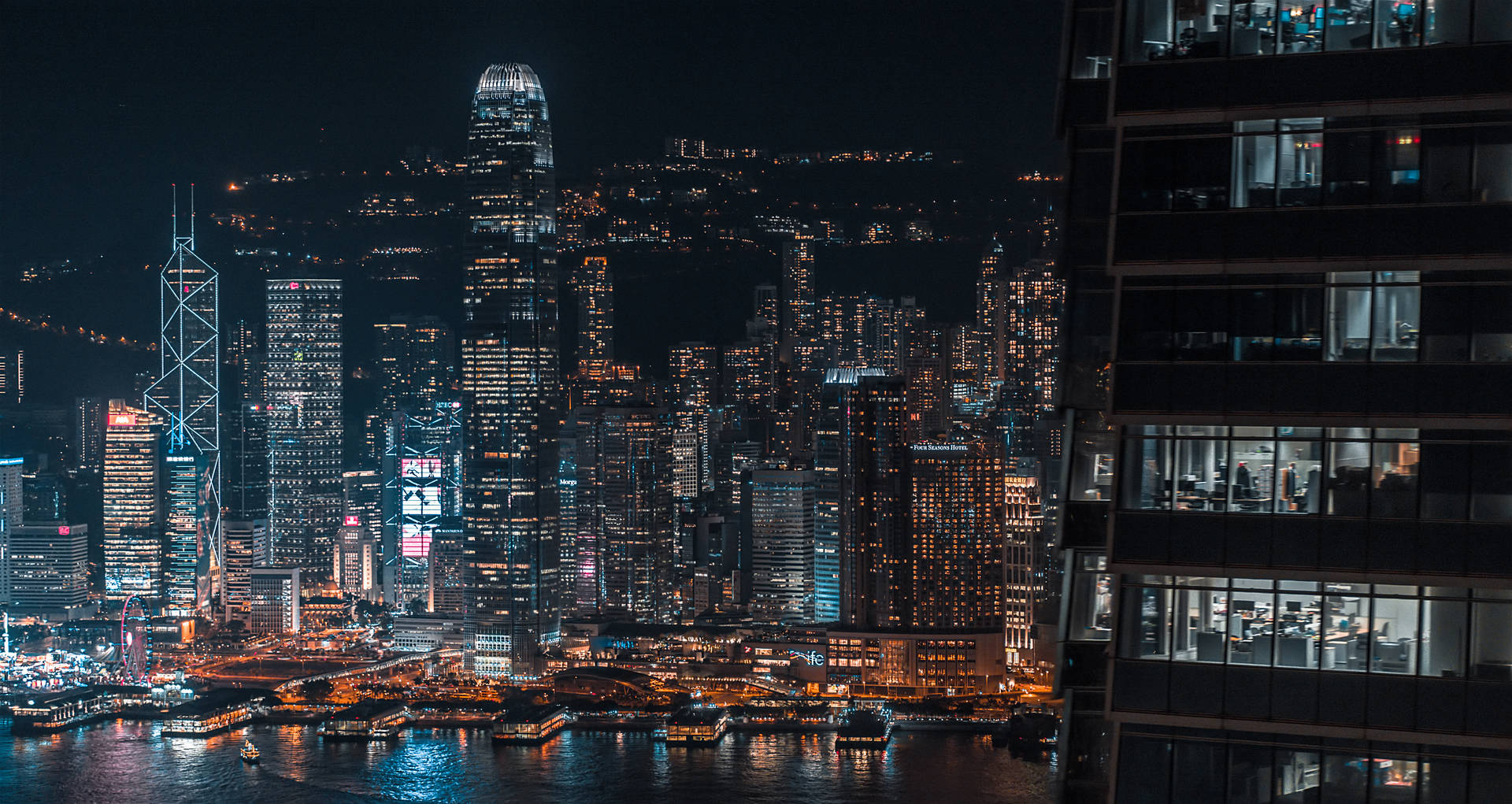 夜間香港天際線，閃爍的摩天大樓和港口倒影。