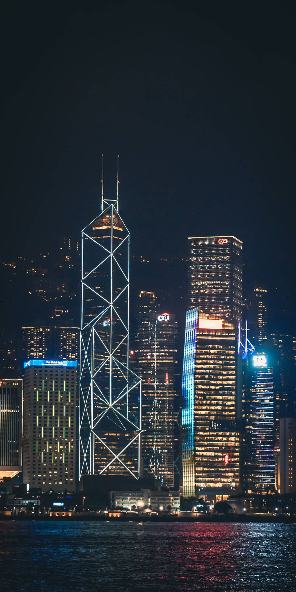 香港天際線夜景燈光 壁紙 — 香港夜景天際線，在深黑色天空下，明亮的摩天大樓倒映在黑暗的水面上。