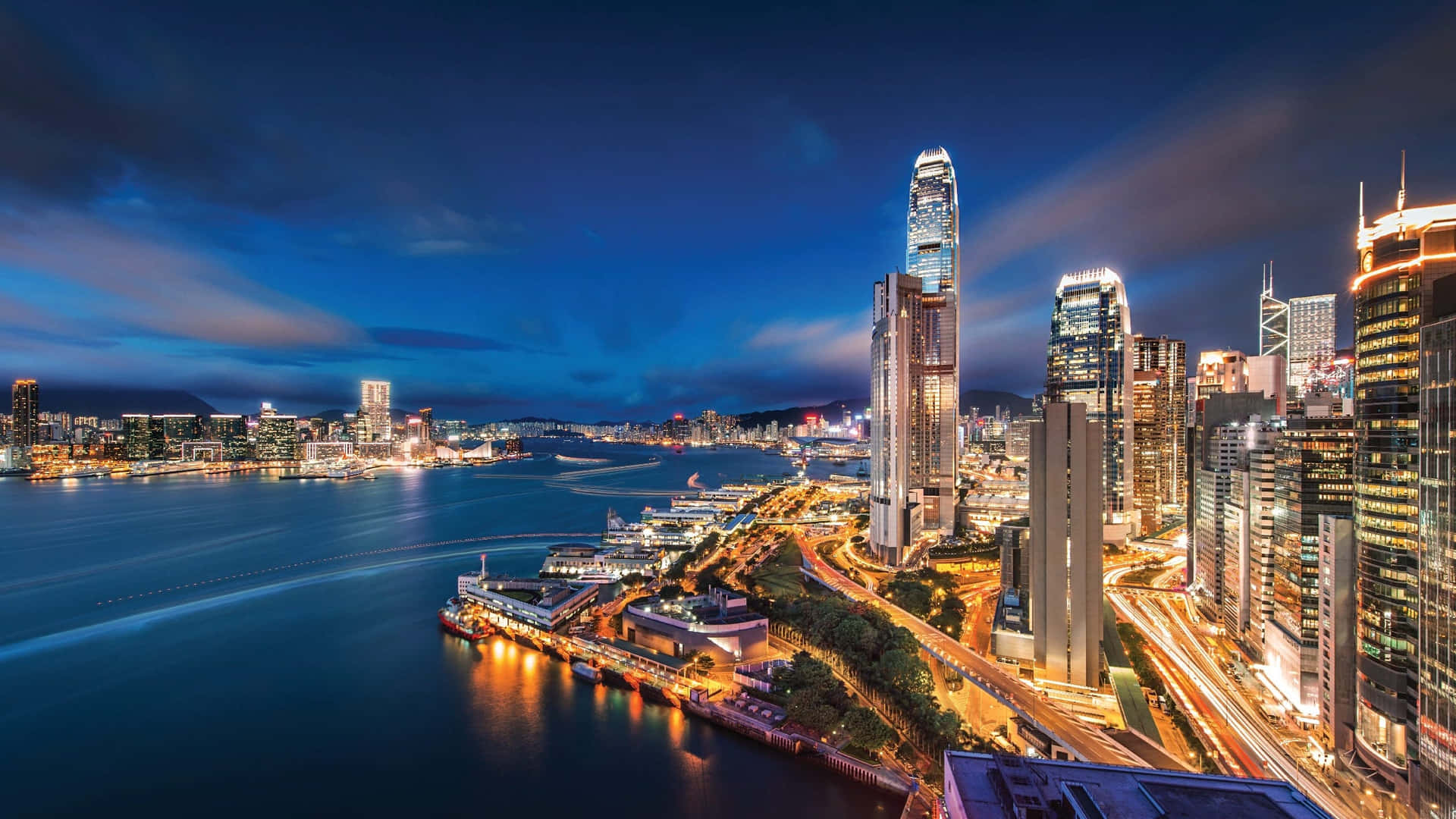 香港天際線黃昏美景 壁紙 — 香港天際線在暮色中的耀眼景色，發光的摩天大樓倒映在港口水面上。