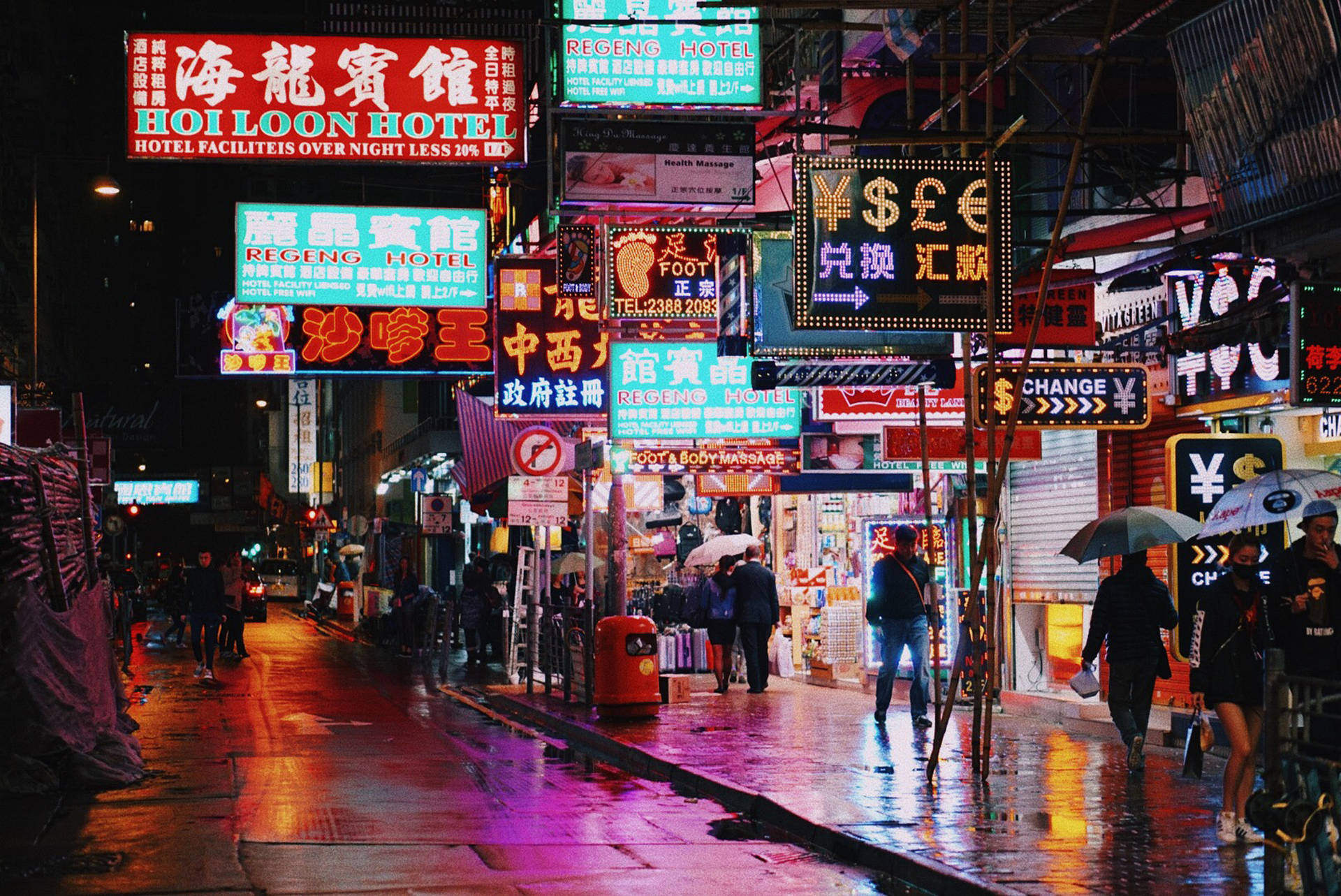 夜雨中的繁華霓虹城市街道，行人撐傘。