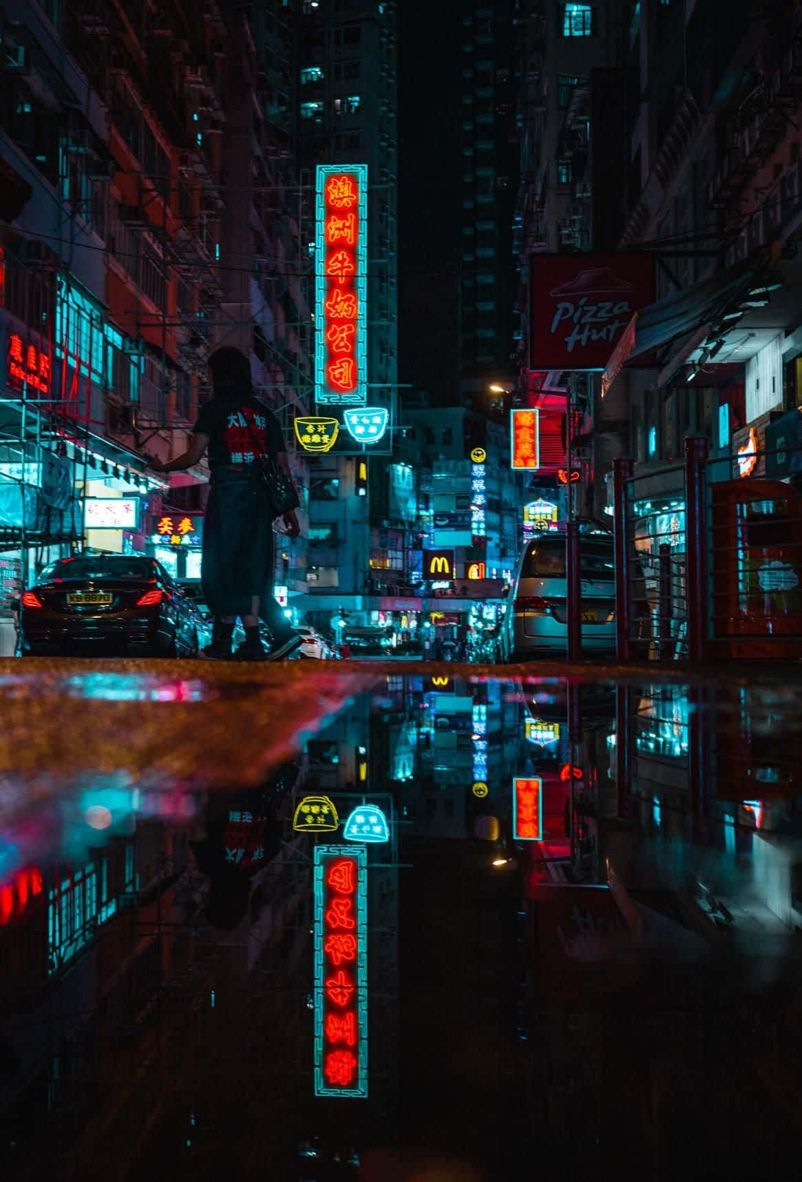 夜晚在霓虹燈閃爍的街道上行走的人，水窪中有倒影。