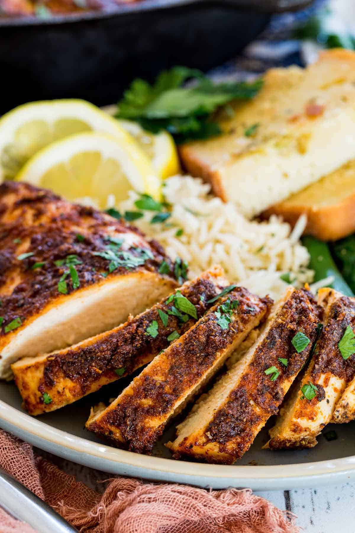 Blackened Chicken 桌布 壁紙 — 香草調味雞胸肉切片，搭配米飯、檸檬角和麵包，盛載於鄉村風格碟子上。