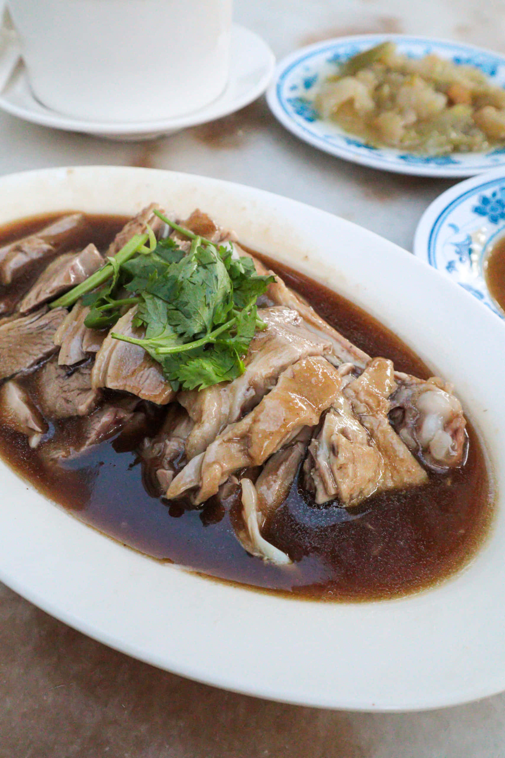 馬來西亞鴨飯：Kam Heong 餐廳 壁紙 — 白碟上嘅蒸雞特寫，配以濃郁深色醬汁同新鮮芫荽裝飾。