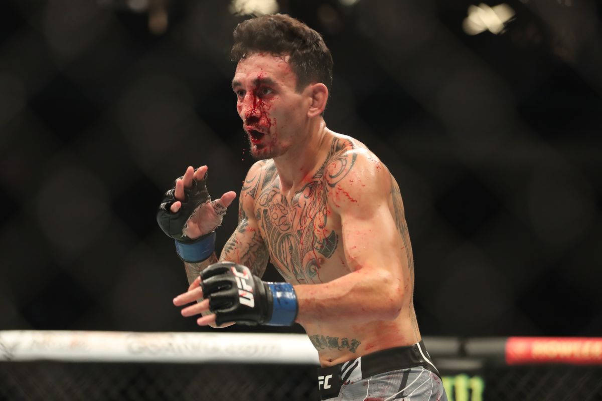 一名滿臉鮮血、帶有紋身的勝利MMA拳手在八角籠內慶祝。