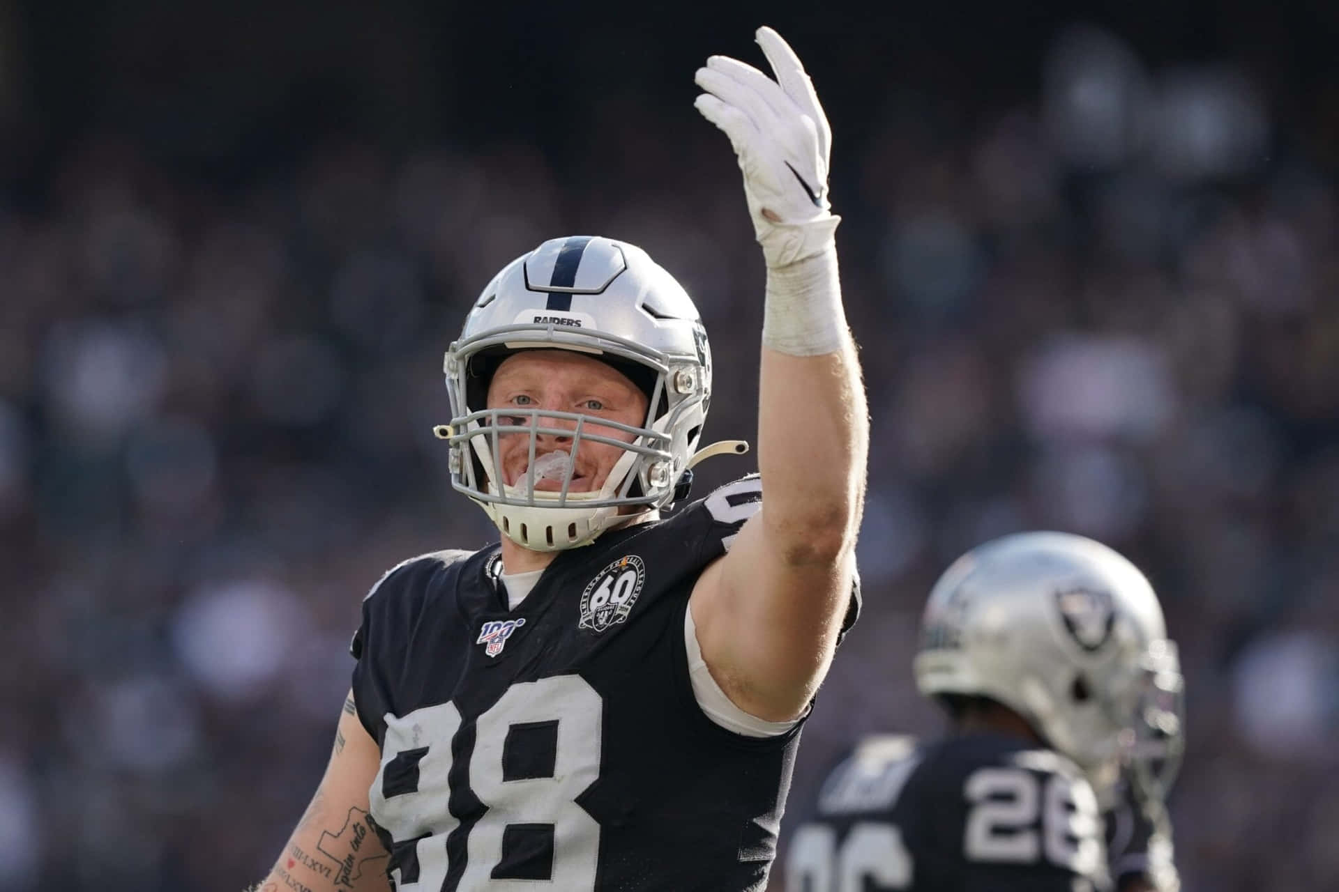 足球員在比賽中穿著Raiders裝備向球迷揮手。