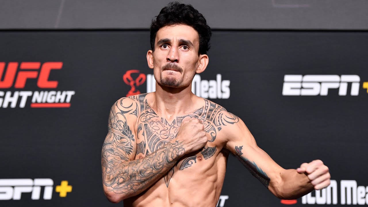有紋身的UFC拳手在稱重活動中擺姿勢，背景有ESPN和UFC標誌。