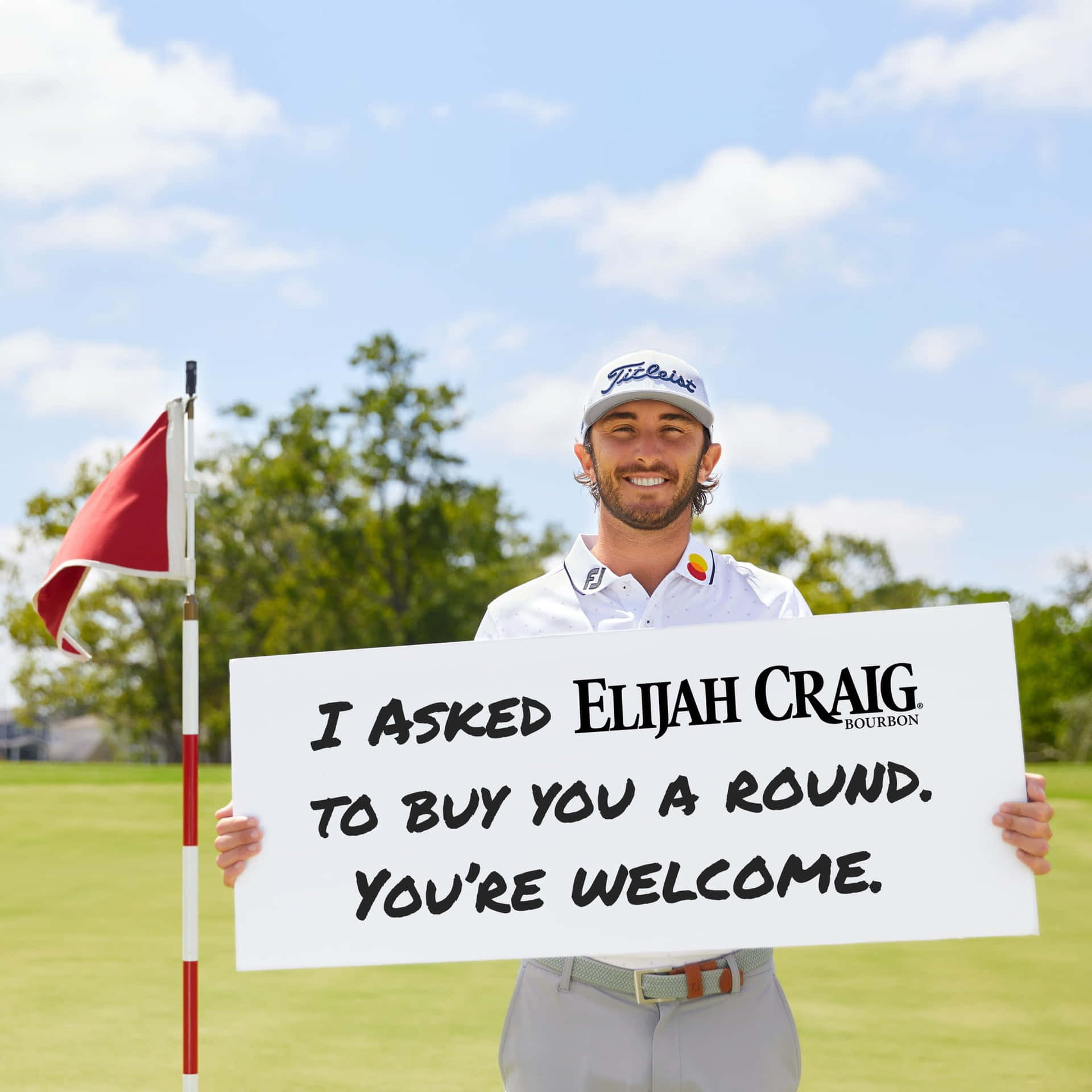 高爾夫球手在陽光明媚的高爾夫球場上舉著提供Elijah Craig波本威士忌回合的牌子。