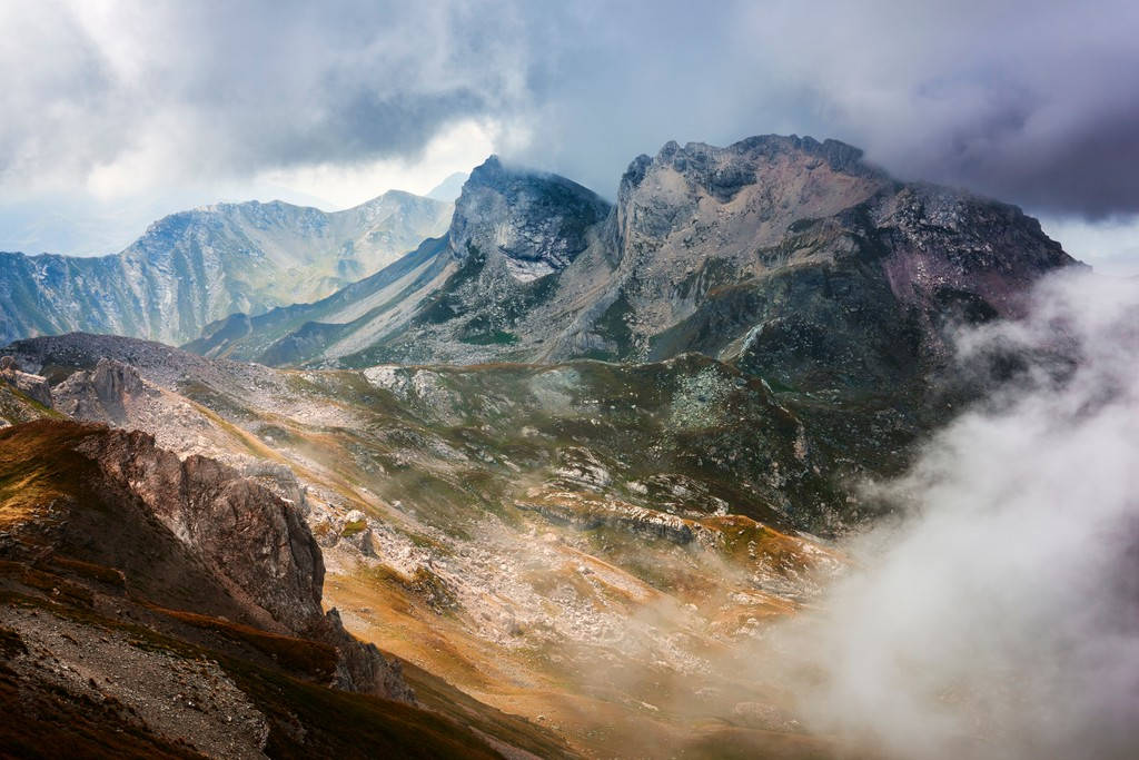 馬其頓科拉布山 壁紙 — 在陰天天空下，一個戲劇性的山脈，有鋸齒狀的山峰和霧氣在岩石山谷中盤旋。