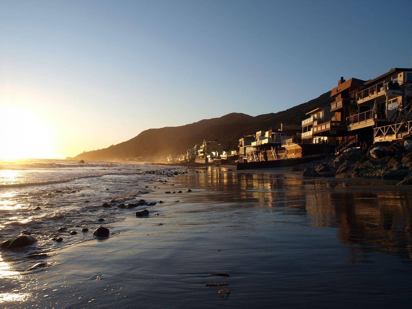 夕陽下的沿海小鎮，海浪和山脈背景