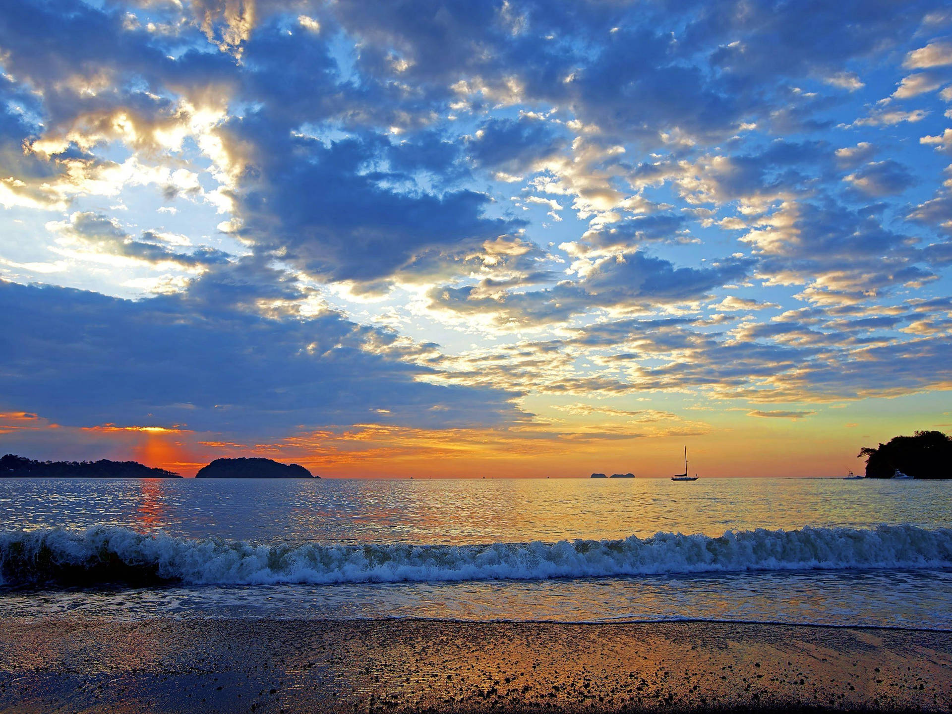海上夕陽，帆船與拍岸浪花，沙灘