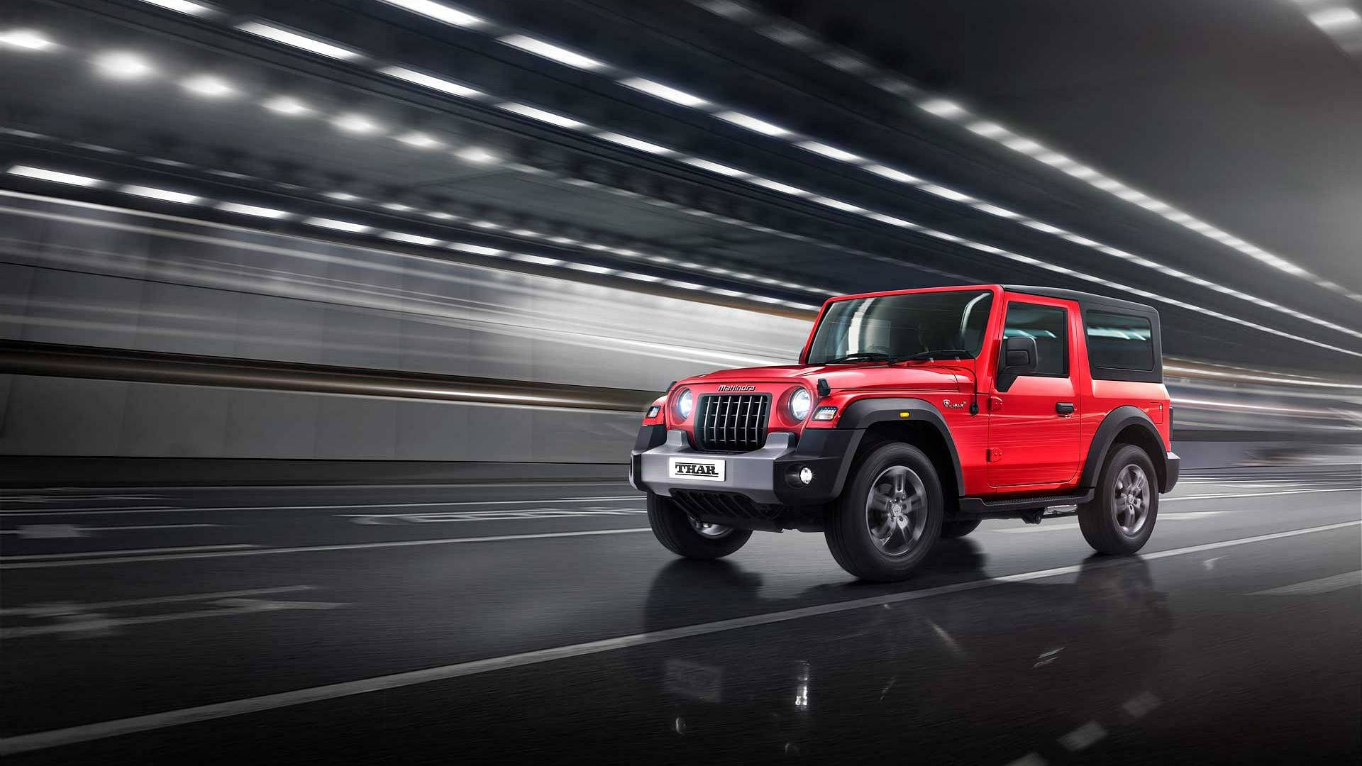 紅色Mahindra Thar SUV在夜間隧道中疾馳，帶有條紋燈光。