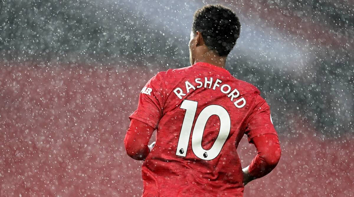 足球員身穿紅色球衣，印有Rashford名字和10號，站在雨中。