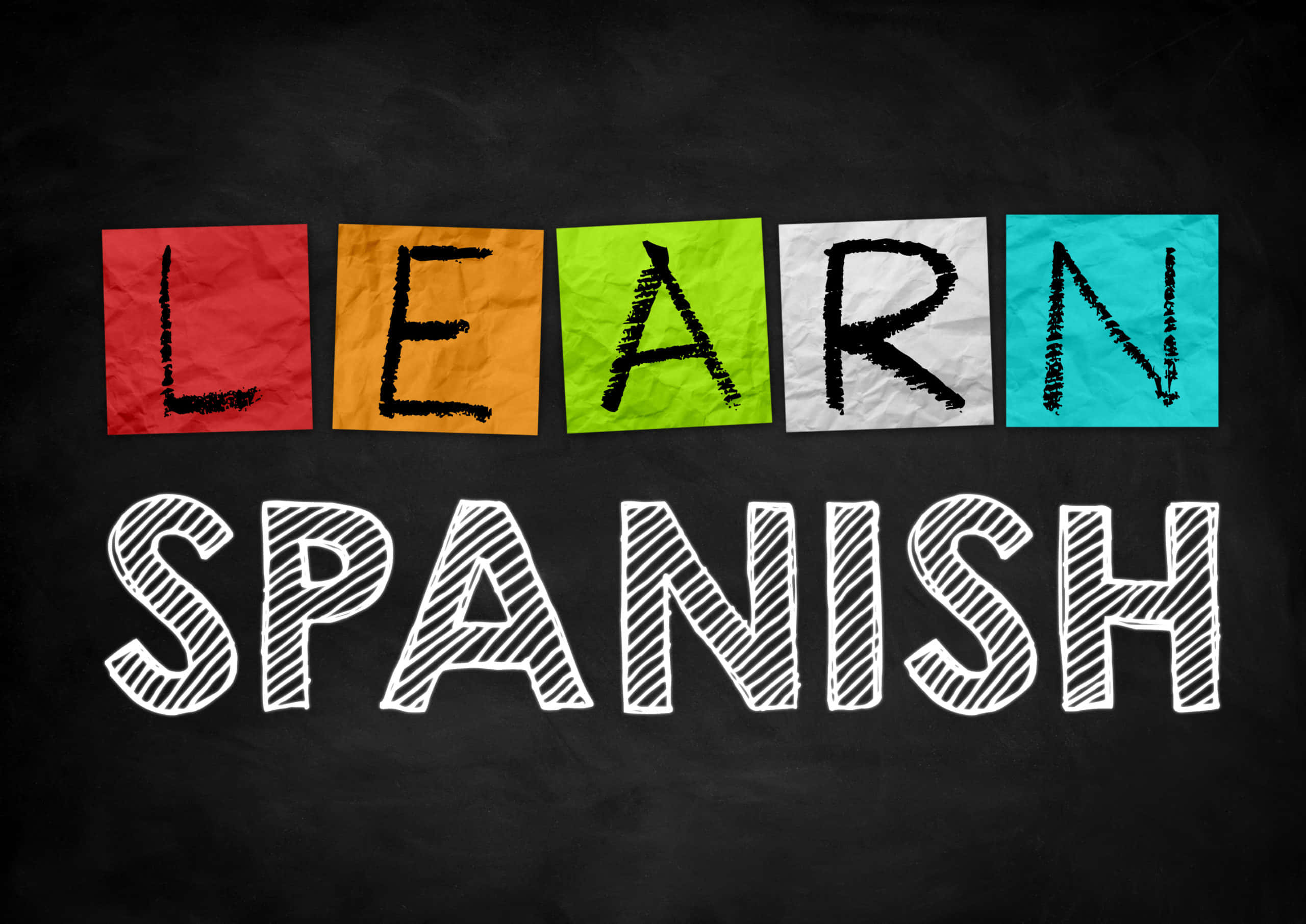 馬德里的彩色城市景觀 壁紙 — 在黑板上用粉筆風格拼出「SPANISH」上方「LEARN」的大膽彩色紙字母。
