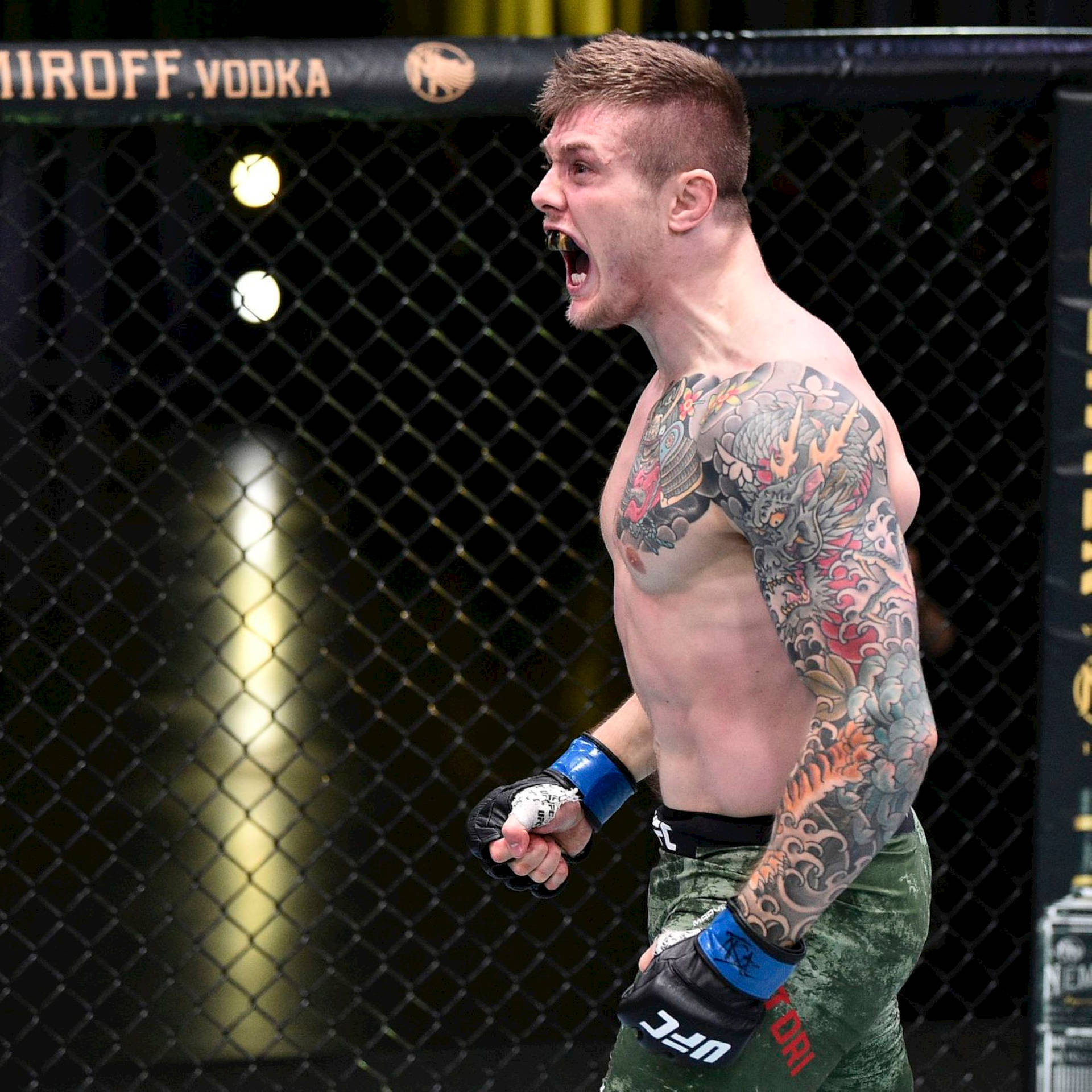 紋身MMA拳手在八角籠內慶祝勝利。
