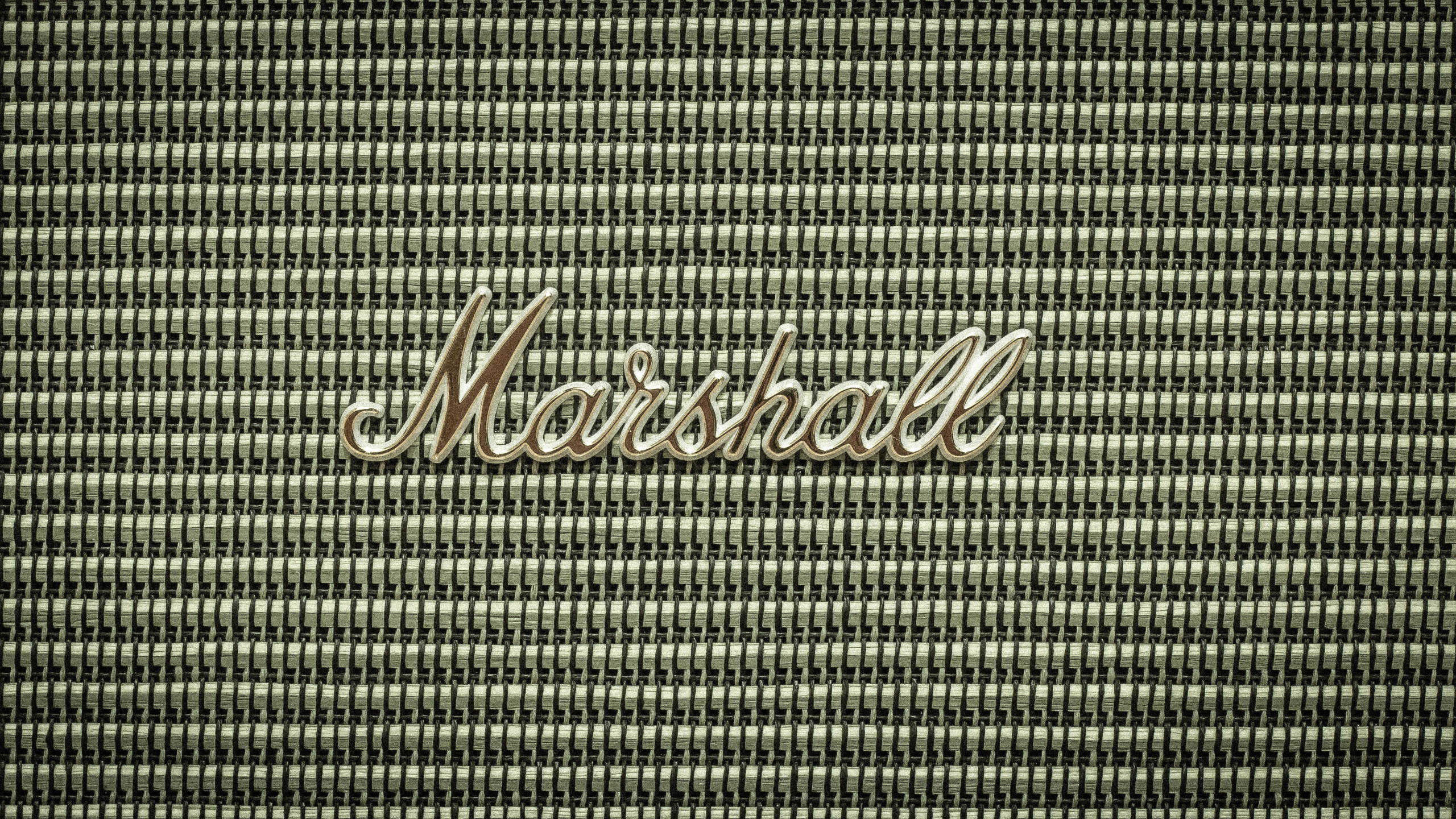 馬歇爾標誌於網格音箱幕布 壁紙 — 復古Marshall擴音器格柵的特寫，帶有金屬標誌，背景為紋理織物。