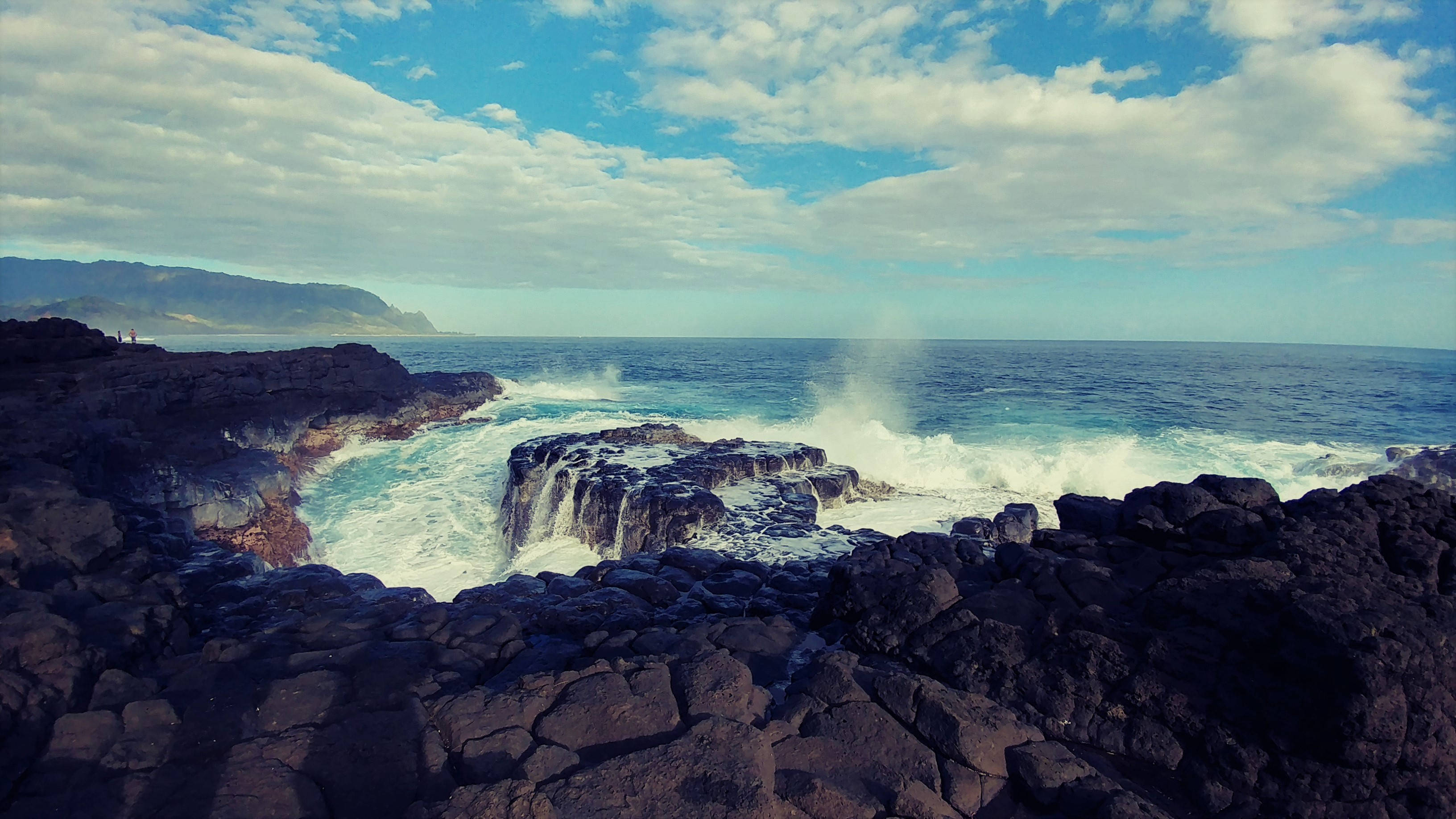 馬爾代夫岩石海岸 壁紙 — 強勁的海浪拍打著深色火山岩，天空湛藍，白雲點綴。