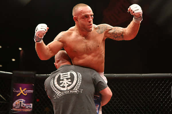一位勝利的MMA拳手在籠中被教練舉起。