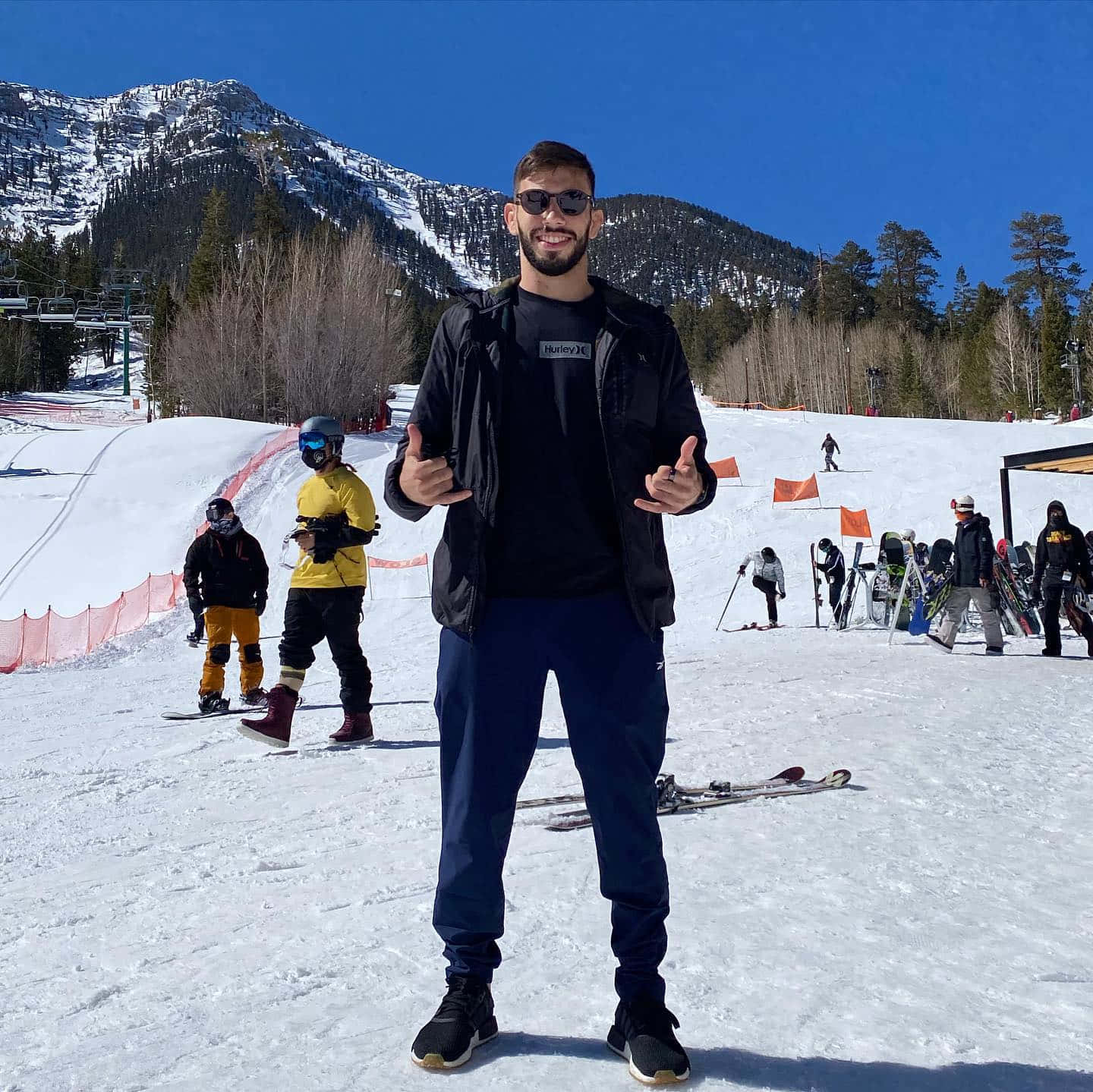 男人在雪坡上豎起大拇指，背後有山脈。