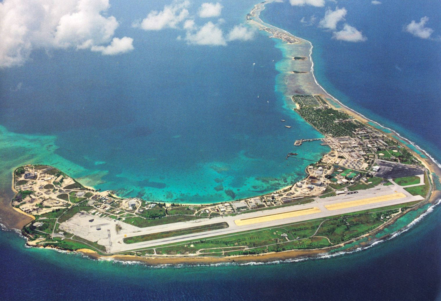 馬紹爾群島夸拉傑因環礁 壁紙 — 一個長形熱帶島嶼的鳥瞰圖，島上有一個跑道機場，周圍環繞著碧綠色的潟湖和深藍色的海洋。