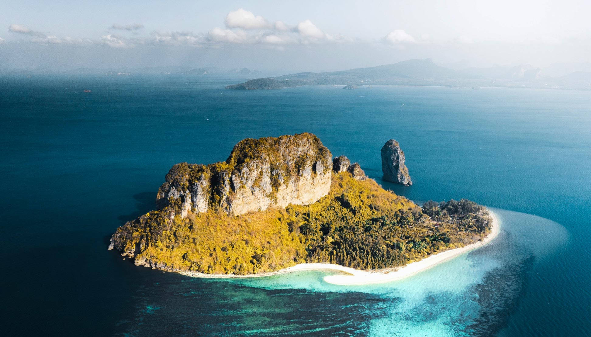 馬紹爾群島寧靜岩岸風光 壁紙 — 俯瞰一個鬱鬱蔥蔥的熱帶島嶼，擁有白色沙灘和碧綠潟湖，被深藍色海洋環繞。