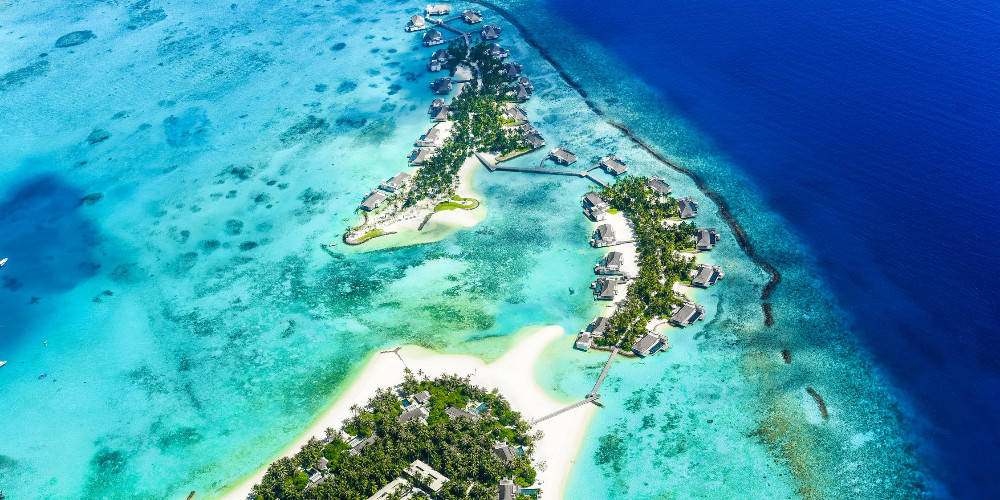 馬紹爾群島空中景觀 壁紙 — 豪華熱帶島嶼度假村的鳥瞰圖，水上平房坐落在清澈碧綠的海水中。