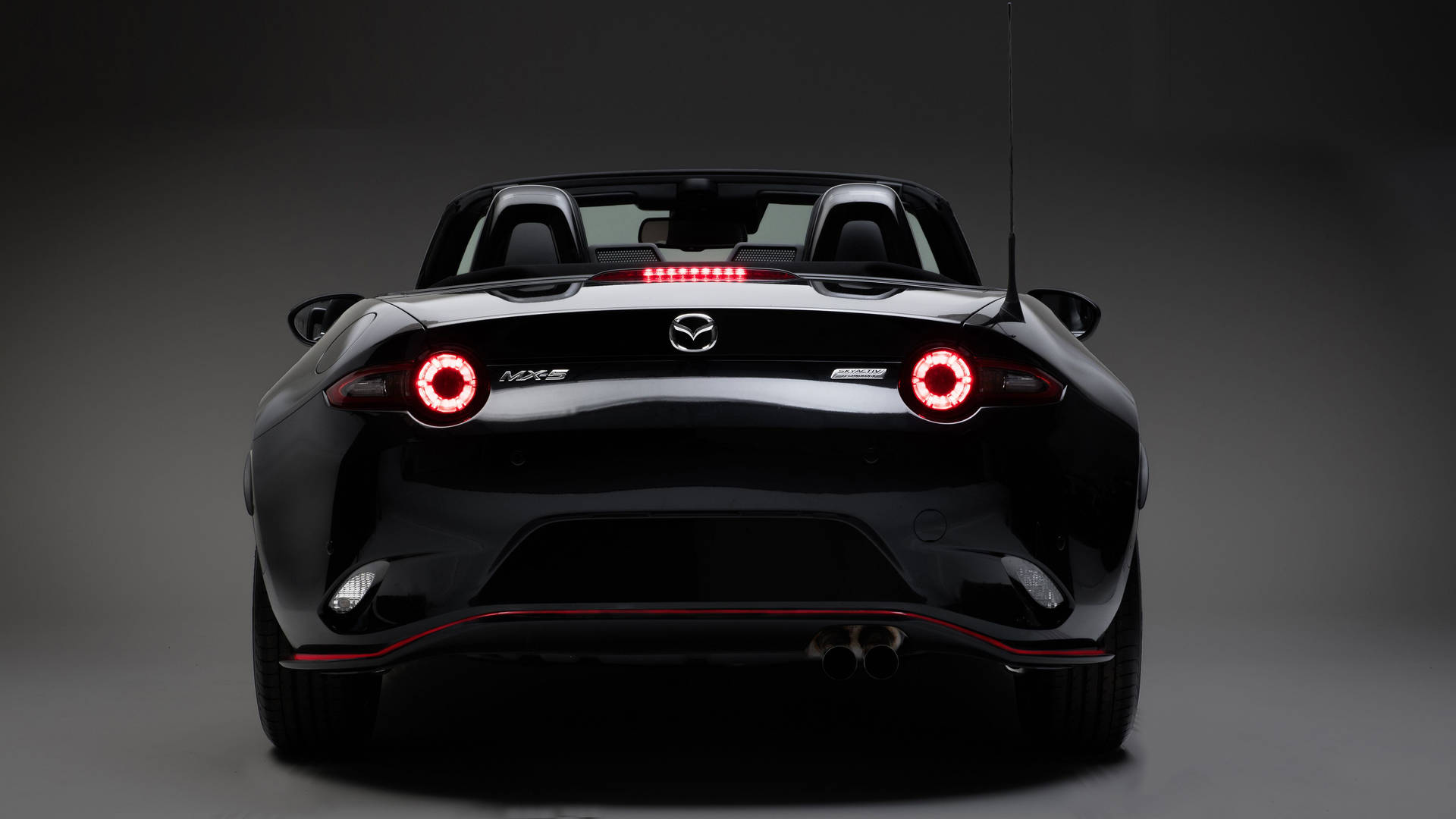 黑色Mazda MX-5 Miata開篷跑車後視圖，在攝影棚中帶有發光的紅色尾燈。