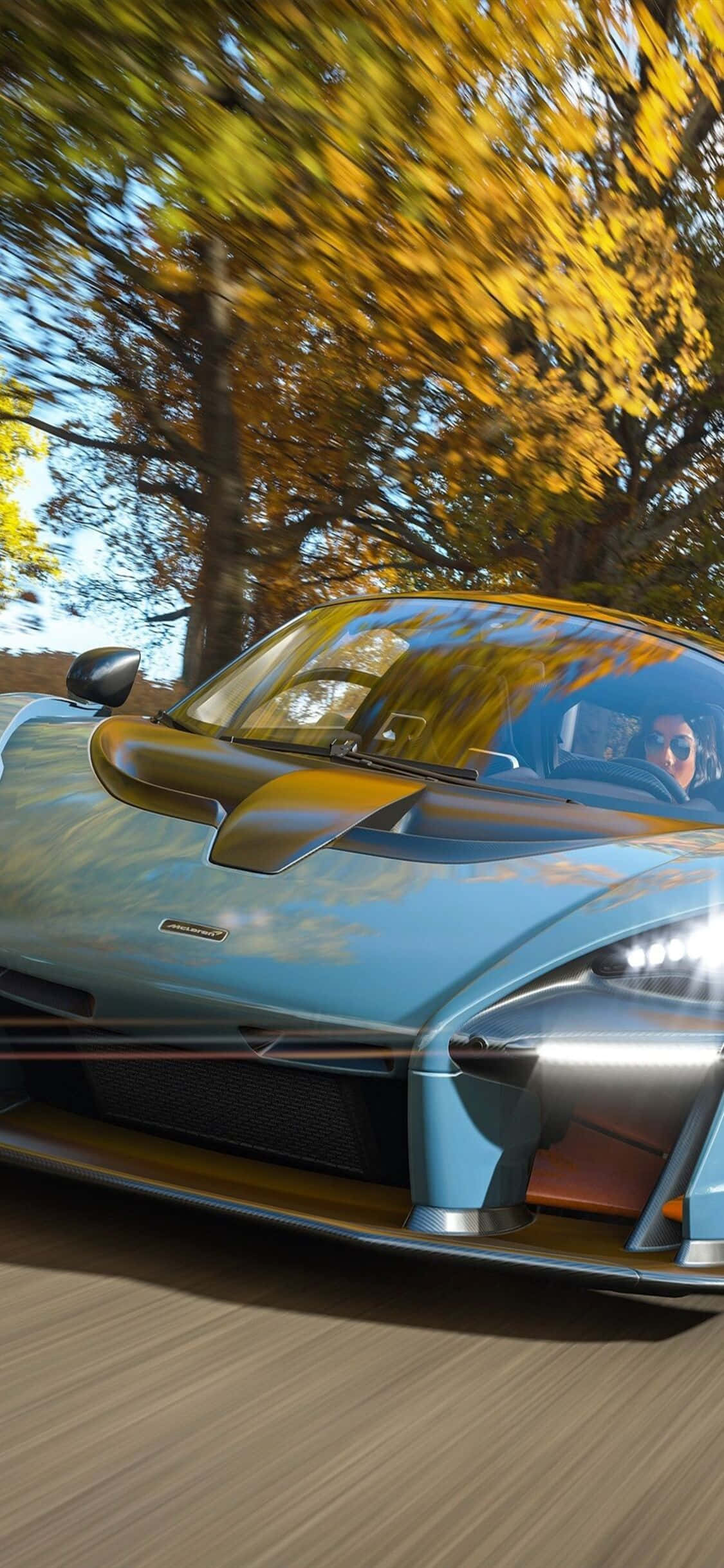 馬自達RX-7 iPhone X《極限競速7》背景 壁紙 — 一輛淺藍色McLaren超級跑車在模糊的動感和鮮豔的樹葉中穿過金色的秋日森林。