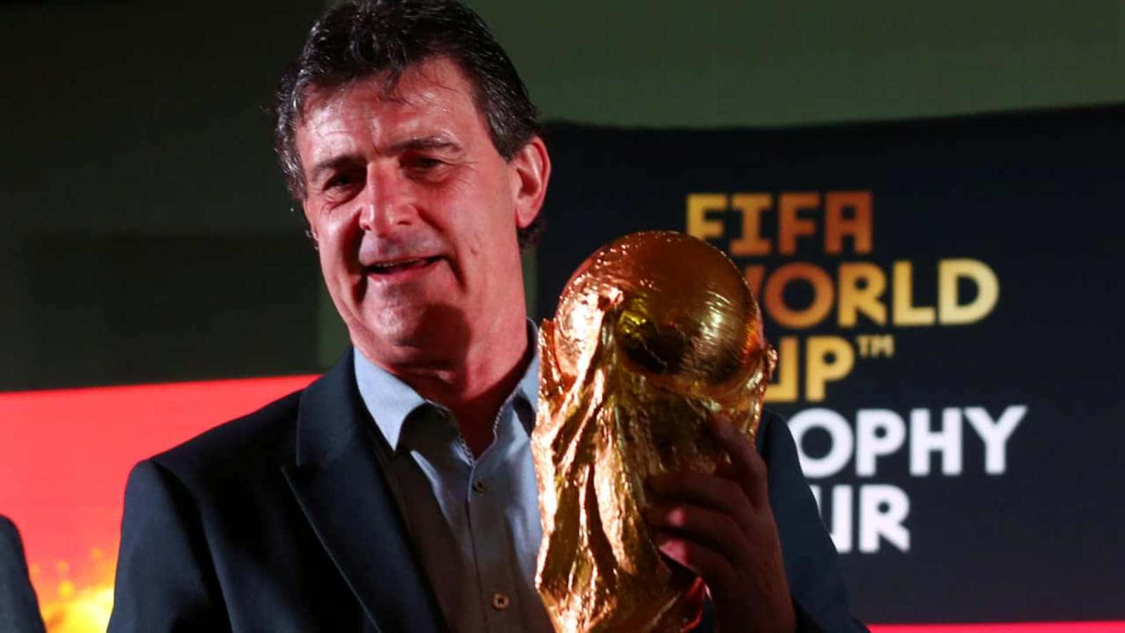 活動中穿西裝的男子手持FIFA世界盃獎盃