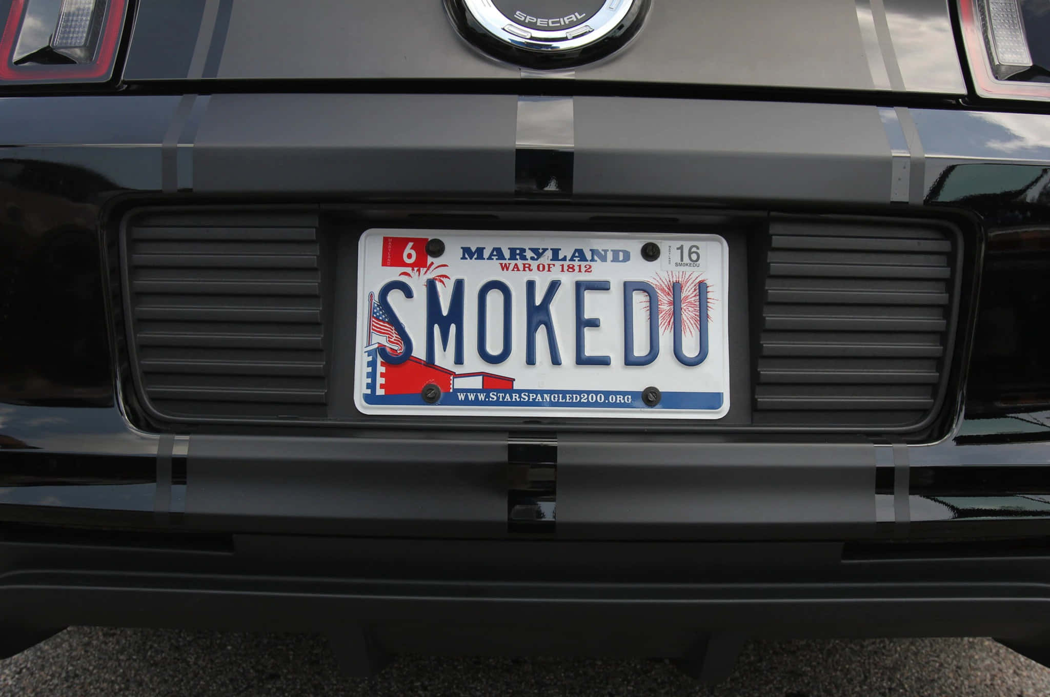 Car License Plate 桌布 壁紙 — 馬里蘭州車牌特寫，上面寫著「SMOKEDU」，安裝在一輛帶有鍍鉻裝飾的黑色肌肉車尾部。
