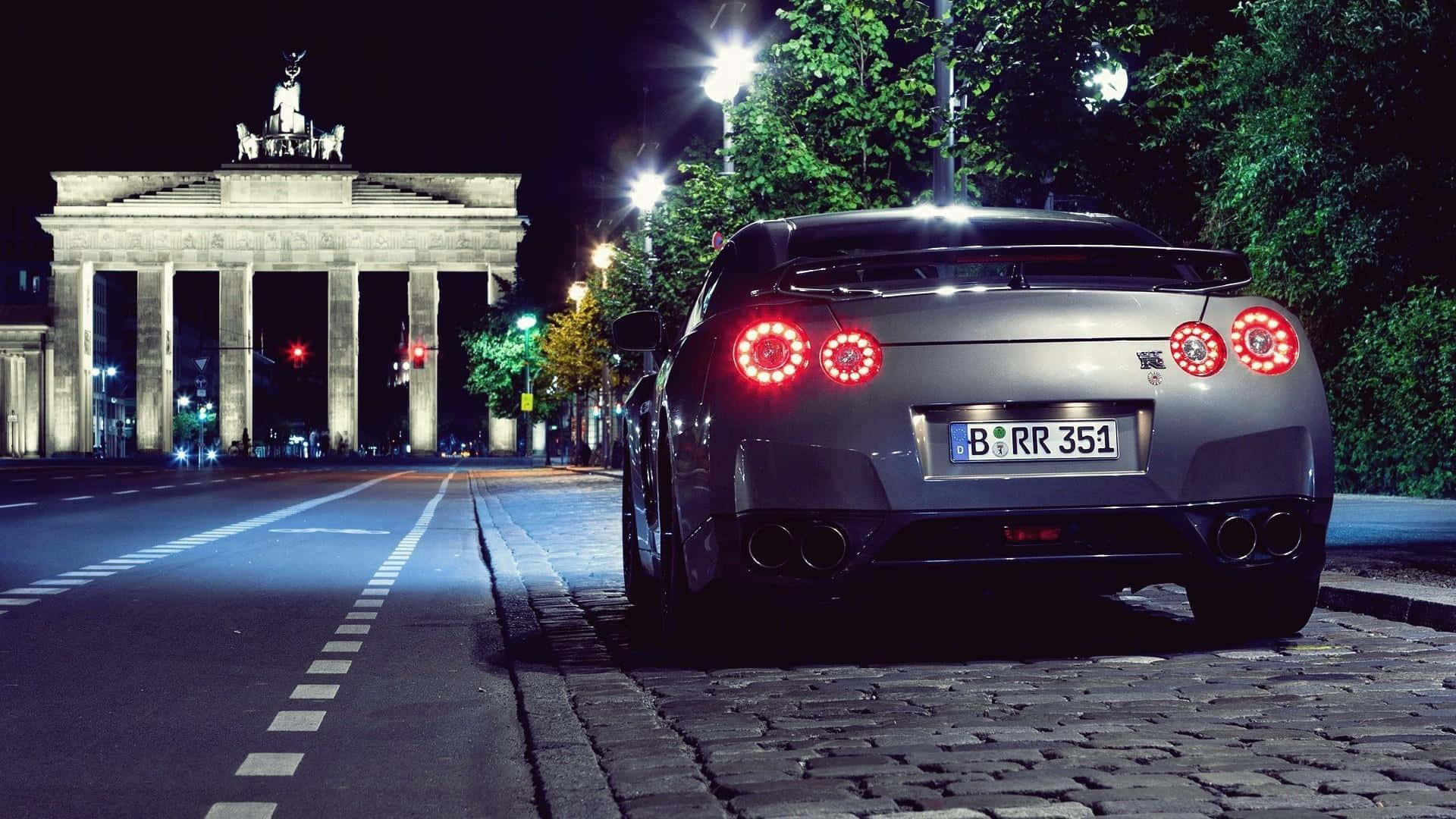 夜間停在柏林勃蘭登堡門前的銀色日產GT-R。