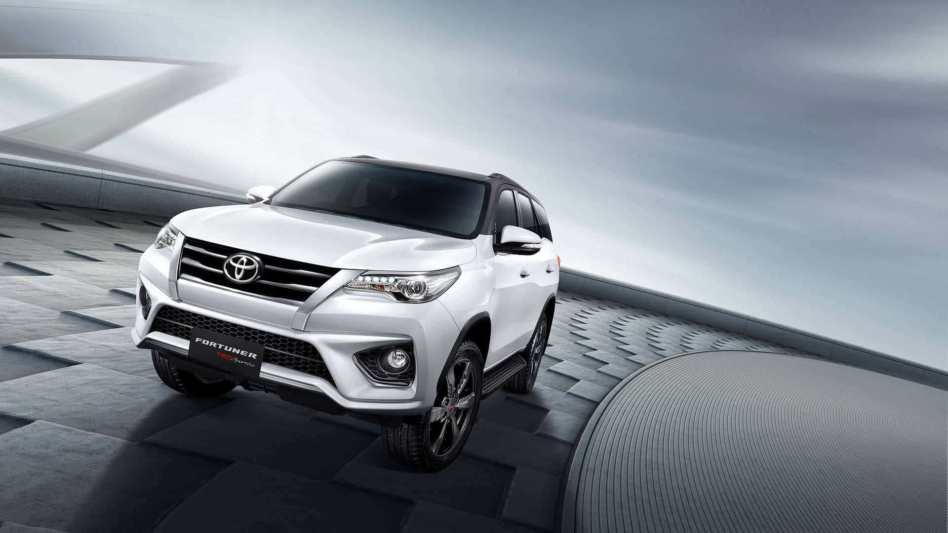 白色豐田 Fortuner SUV 在未來感灰色平台上，帶有戲劇性燈光。