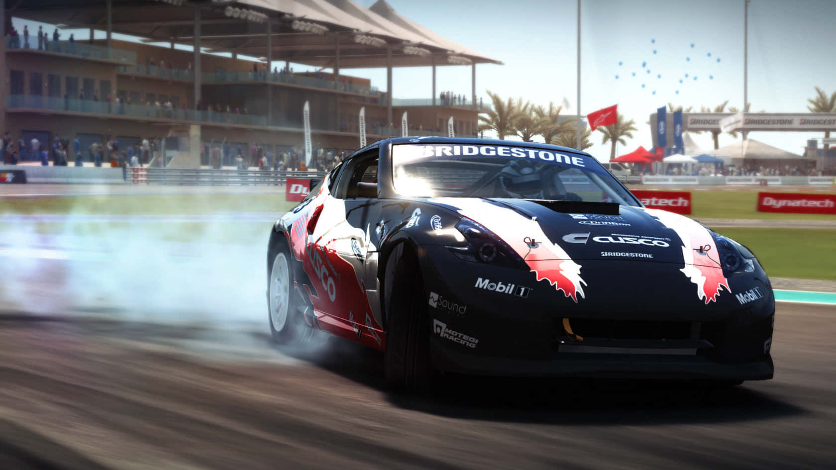 駕馭Grid Autosport，挑戰極限賽車 壁紙 — 一輛黑紅色的賽車在陽光明媚的賽道上漂移，煙霧翻騰，周圍是看台和棕櫚樹。