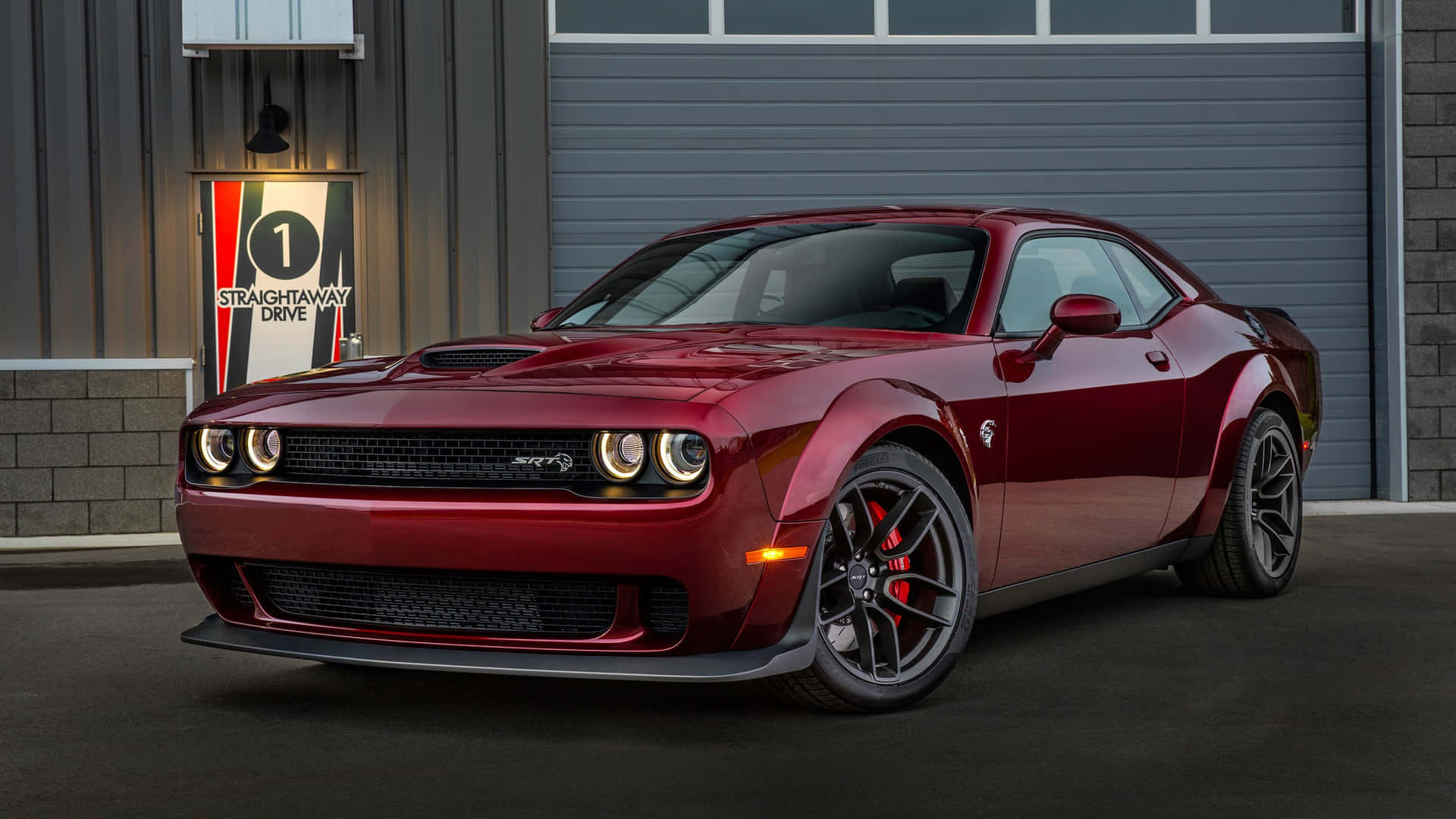 紅色Dodge Challenger SRT Hellcat停放在一個帶有照明標誌的車庫前。