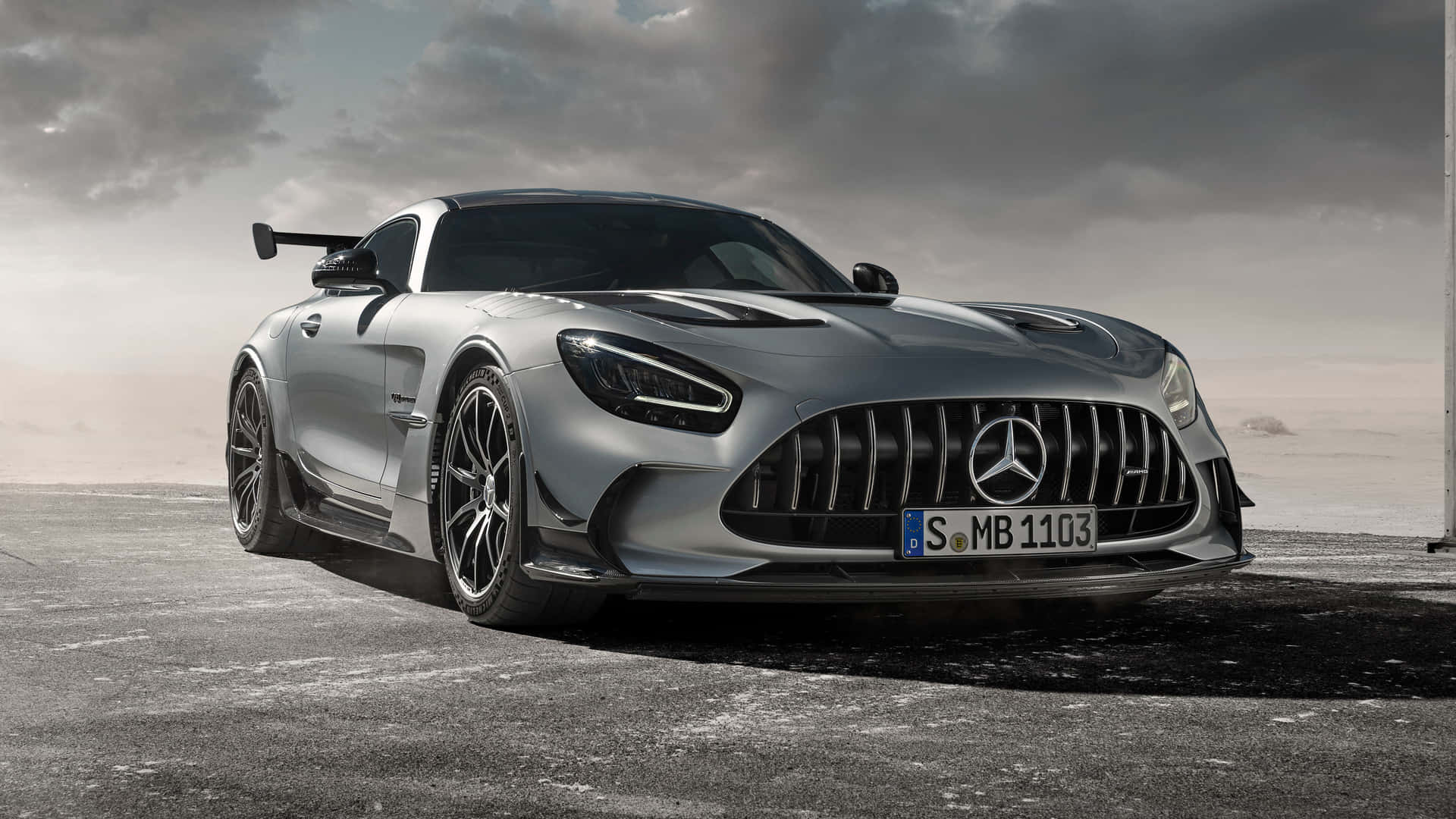 多雲天空下混凝土上的銀色 Mercedes-AMG GT Black Series 跑車。