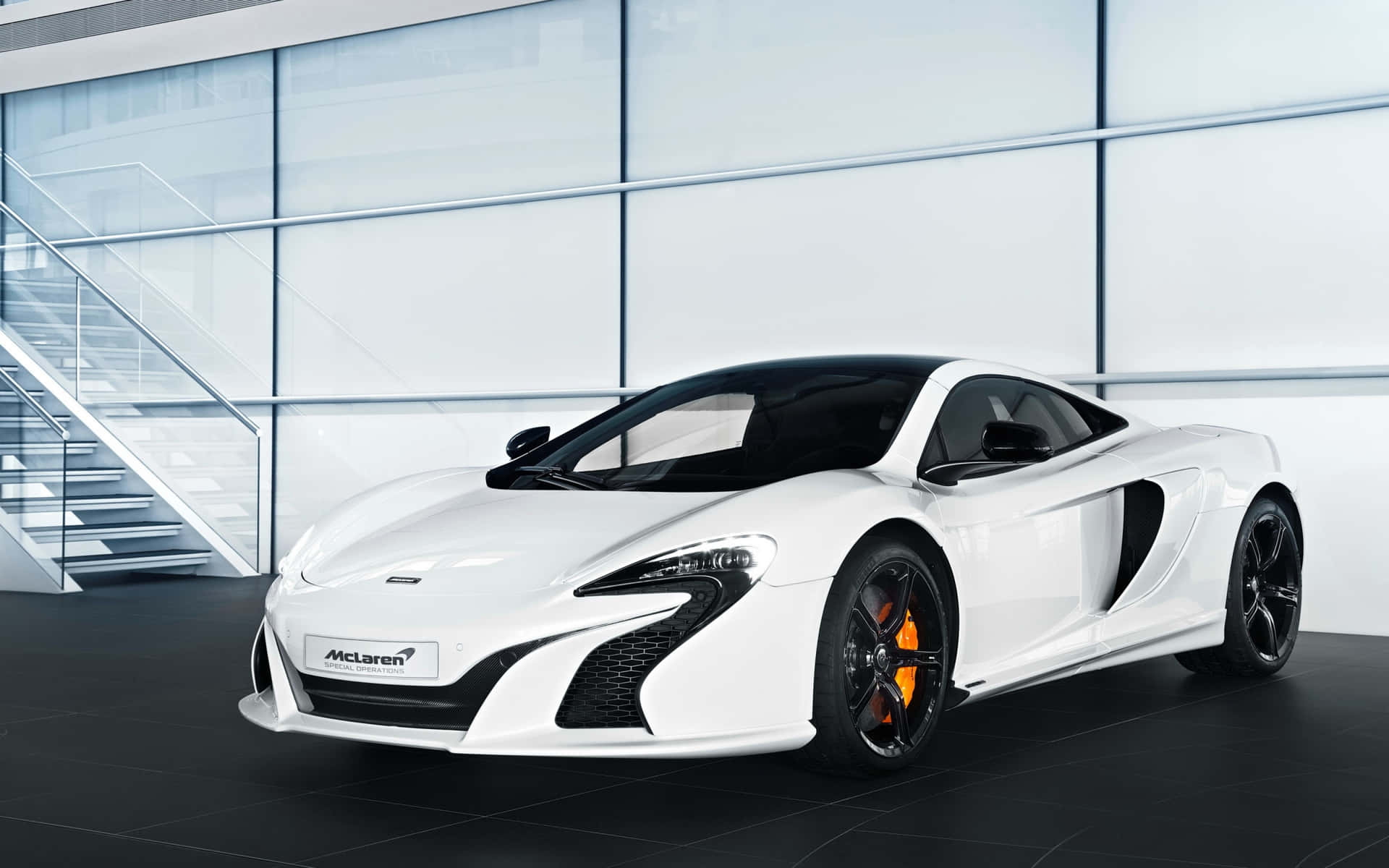 白色McLaren跑車配橙色制動器，在現代玻璃陳列室中。